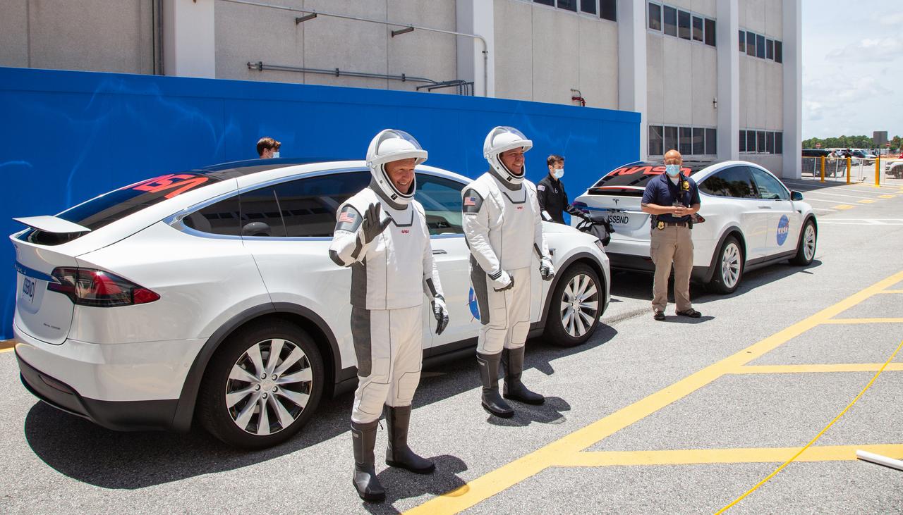 On May 23, 2020, NASA astronauts Robert Behnken (right) and Douglas Hurley pose for a photo as they prepare to take a ride in a Tesla that will transport them from the Neil A. Armstrong Operations and Checkout Building to historic Launch Complex 39A on launch day at the Kennedy Space Center in Florida during a full dress rehearsal ahead of NASA’s SpaceX Demo-2 launch. A SpaceX Falcon 9 rocket and Crew Dragon spacecraft will carry Behnken and Hurley to the International Space Station as part of the agency’s Commercial Crew Program, returning human spaceflight capability to the U.S. after nearly a decade. Launch is slated for 4:33 p.m. EDT on Wednesday, May 27.