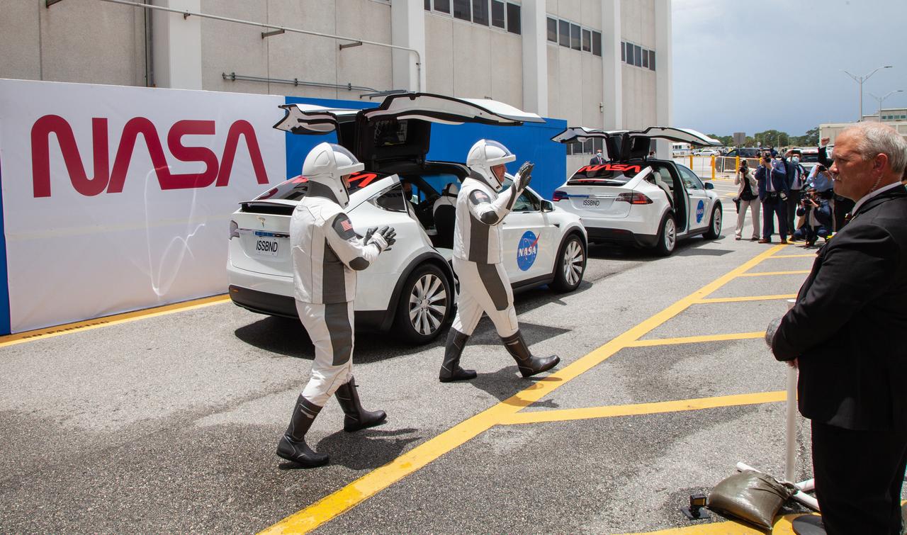 NASA astronauts Douglas Hurley (left) and Robert Behnken wave as they exit the Neil A. Armstrong Operations and Checkout Building at the agency’s Kennedy Space Center in Florida in preparation for transport to Launch Complex 39A to launch on NASA’s SpaceX Demo-2 mission. The launch, initially scheduled for May 27, 2020, was scrubbed due to unfavorable weather conditions around Launch Complex 39A. The next launch attempt will be Saturday, May 30. Liftoff of the SpaceX Falcon 9 rocket and Crew Dragon spacecraft is scheduled for 3:22 p.m. EDT from historic Launch Complex 39A. Behnken and Hurley will be the first astronauts to launch to the International Space Station from U.S. soil since the end of the Space Shuttle Program in 2011. Part of NASA’s Commercial Crew Program, this will be SpaceX’s final flight test, paving the way for the agency to certify the crew transportation system for regular, crewed flights to the orbiting laboratory.