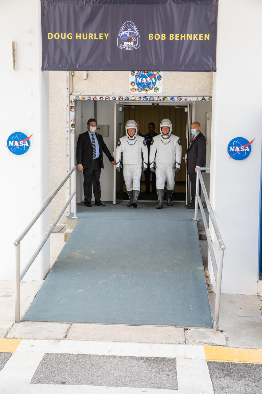 NASA astronauts Douglas Hurley (left) and Robert Behnken exit the Neil A. Armstrong Operations and Checkout Building at the agency’s Kennedy Space Center in Florida in preparation for transport to Launch Complex 39A to launch on NASA’s SpaceX Demo-2 mission. The launch, initially scheduled for May 27, 2020, was scrubbed due to unfavorable weather conditions around Launch Complex 39A. The next launch attempt will be Saturday, May 30. Liftoff of the SpaceX Falcon 9 rocket and Crew Dragon spacecraft is scheduled for 3:22 p.m. EDT from historic Launch Complex 39A. Behnken and Hurley will be the first astronauts to launch to the International Space Station from U.S. soil since the end of the Space Shuttle Program in 2011. Part of NASA’s Commercial Crew Program, this will be SpaceX’s final flight test, paving the way for the agency to certify the crew transportation system for regular, crewed flights to the orbiting laboratory.