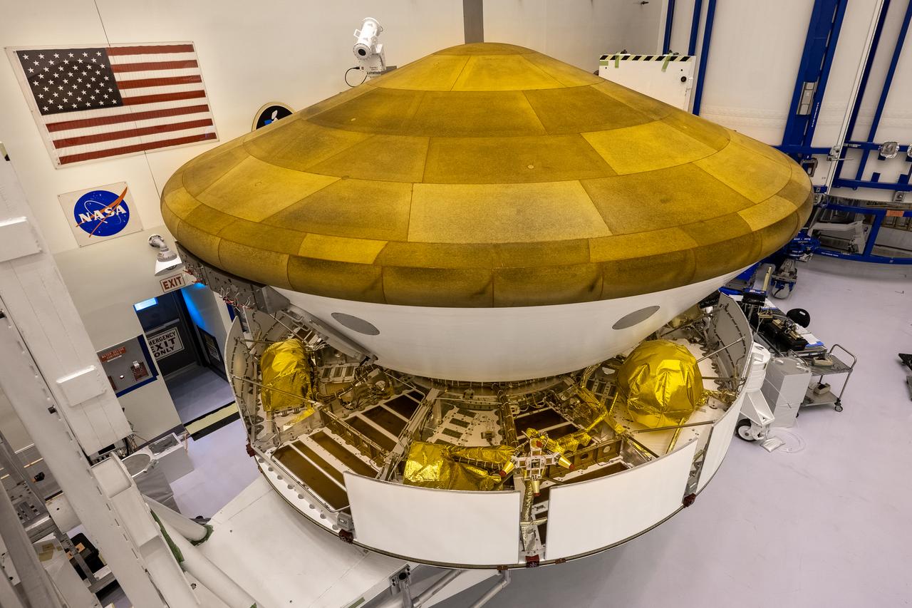 Inside the Payload Hazardous Servicing Facility at NASA’s Kennedy Space Center in Florida, the Backshell-Powered Descent Vehicle, in view, and Entry Vehicle assemblies are being attached to the Mars Perseverance rover on May 29, 2020. The cone-shaped backshell contains the parachute, and along with the mission’s heat shield, provides protection for the rover and descent stage during Martian atmospheric entry. The Mars Perseverance rover is scheduled to launch on July 20 atop a United Launch Alliance Atlas V 541 rocket from Pad 41 at nearby Cape Canaveral Air Force Station. The rover is part of NASA’s Mars Exploration Program, a long-term effort of robotic exploration of the Red Planet. The rover will search for habitable conditions in the ancient past and signs of past microbial life on Mars. The Launch Services Program at Kennedy is responsible for launch management.