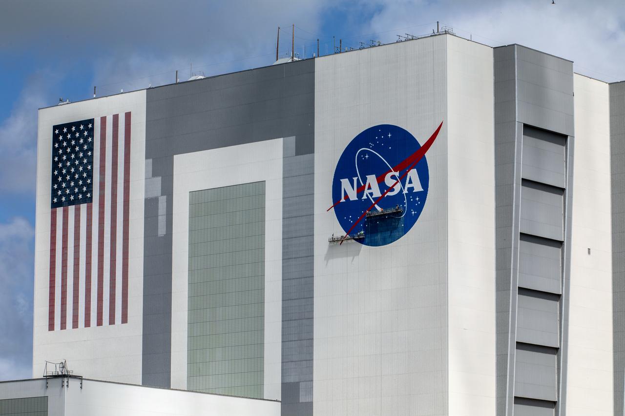 Painting of the NASA logo, also called the meatball, continues on the 525-foot-tall Vehicle Assembly Building (VAB) at the agency’s Kennedy Space Center in Florida on May 29 2020. HM2 and H.I.S. Painting of Titusville, Florida, are repainting the meatball and the American Flag on the iconic building. High Bay 3 inside the VAB has been upgraded with 10 new levels of work platforms that will surround and provide access for service and processing of NASA's Space Launch System (SLS) rocket and Orion spacecraft. Exploration Ground Systems is overseeing upgrades to the VAB to support the launch of the SLS and Orion for Artemis missions. Under the Artemis program, NASA will send the first woman and next man to the Moon.