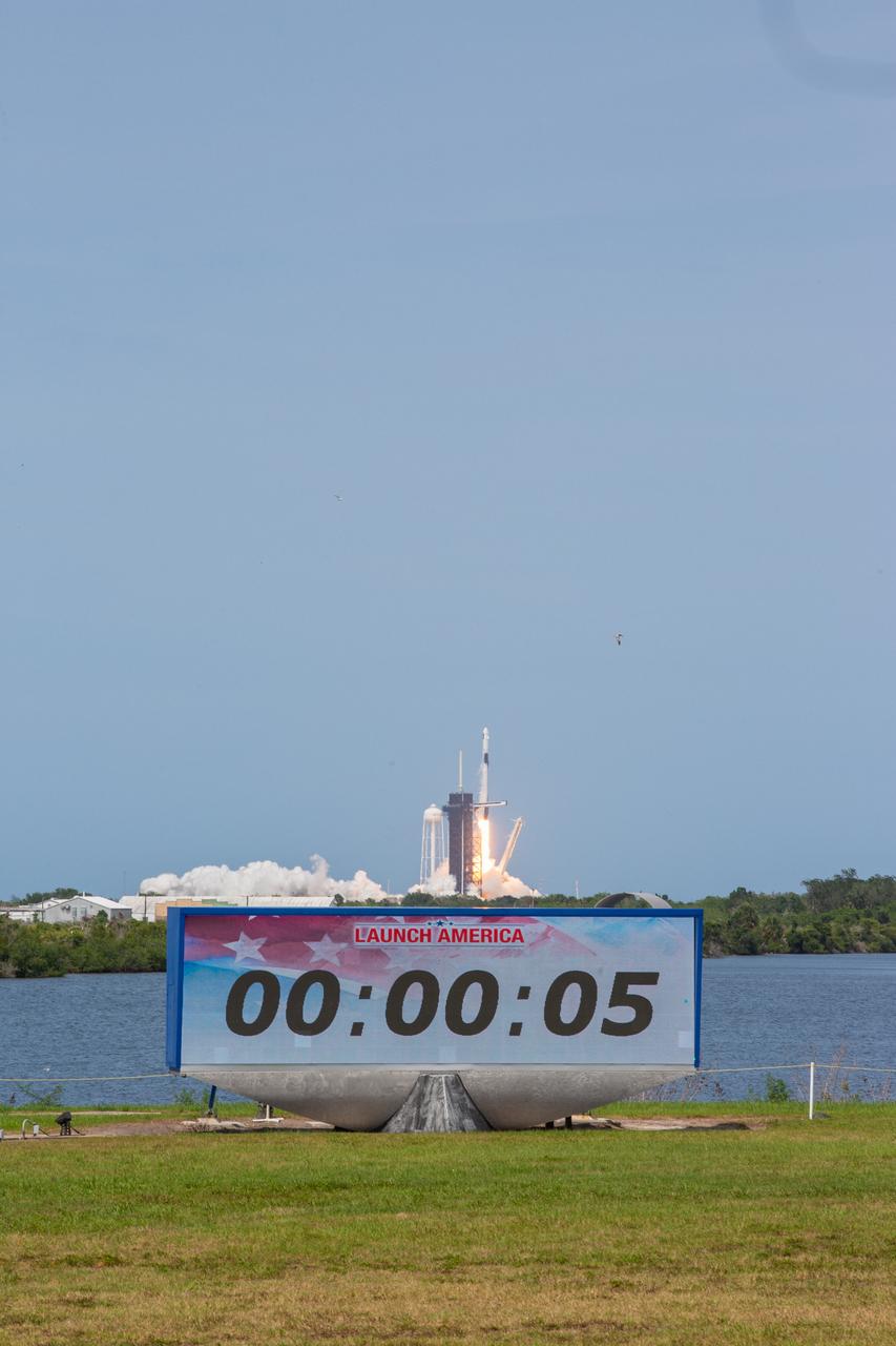With a view of the Press Site countdown clock in the foreground, a SpaceX Falcon 9 rocket and Crew Dragon spacecraft lifts off from Launch Complex 39A at NASA’s Kennedy Space Center in Florida on May 30, 2020, carrying NASA astronauts Robert Behnken and Douglas Hurley to the International Space Station for the agency’s SpaceX Demo-2 mission. Liftoff occurred at 3:22 p.m. EDT. Behnken and Hurley are the first astronauts to launch from U.S. soil to the space station since the end of the Space Shuttle Program in 2011. Part of NASA’s Commercial Crew Program, this will be SpaceX’s final flight test, paving the way for the agency to certify the crew transportation system for regular, crewed flights to the orbiting laboratory.