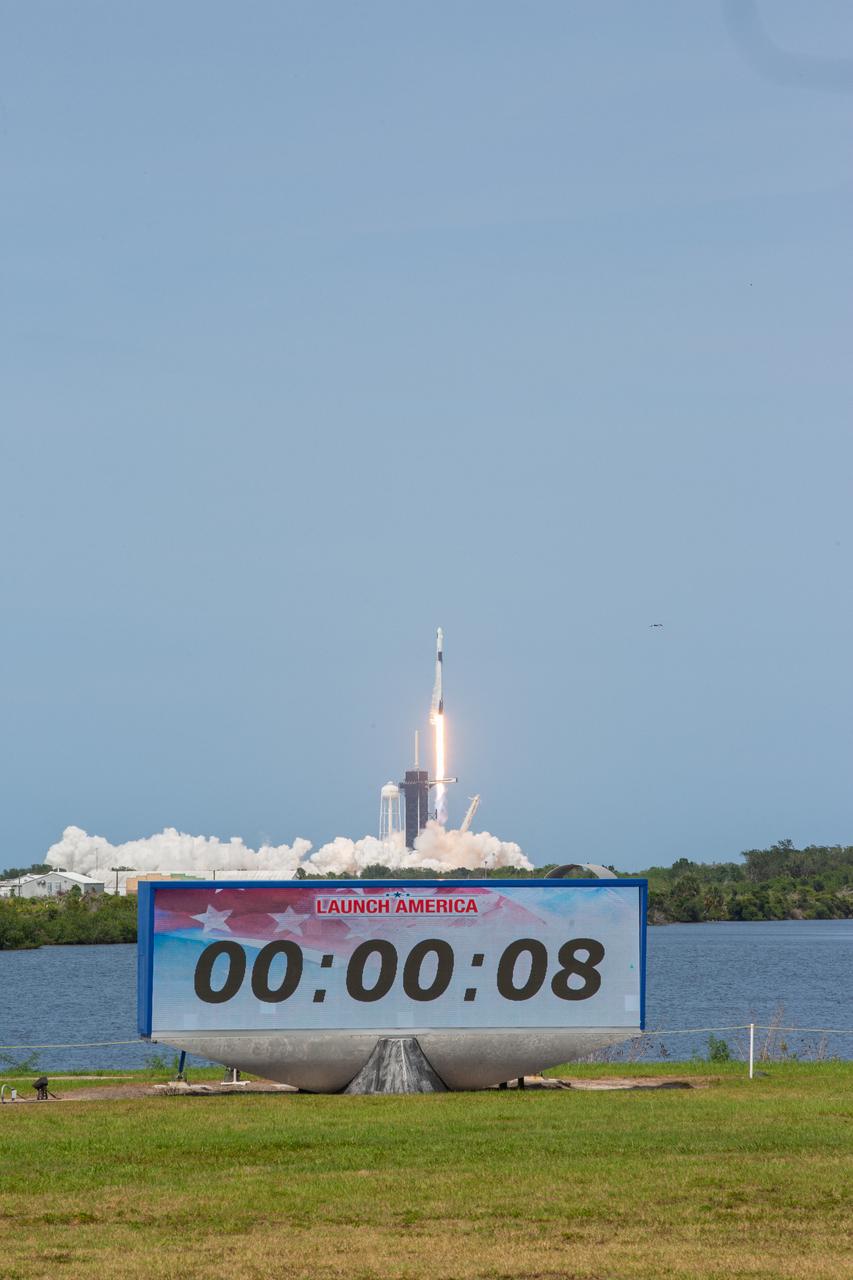 With a view of the Press Site countdown clock in the foreground, a SpaceX Falcon 9 rocket and Crew Dragon spacecraft lifts off from Launch Complex 39A at NASA’s Kennedy Space Center in Florida on May 30, 2020, carrying NASA astronauts Robert Behnken and Douglas Hurley to the International Space Station for the agency’s SpaceX Demo-2 mission. Liftoff occurred at 3:22 p.m. EDT. Behnken and Hurley are the first astronauts to launch from U.S. soil to the space station since the end of the Space Shuttle Program in 2011. Part of NASA’s Commercial Crew Program, this will be SpaceX’s final flight test, paving the way for the agency to certify the crew transportation system for regular, crewed flights to the orbiting laboratory.