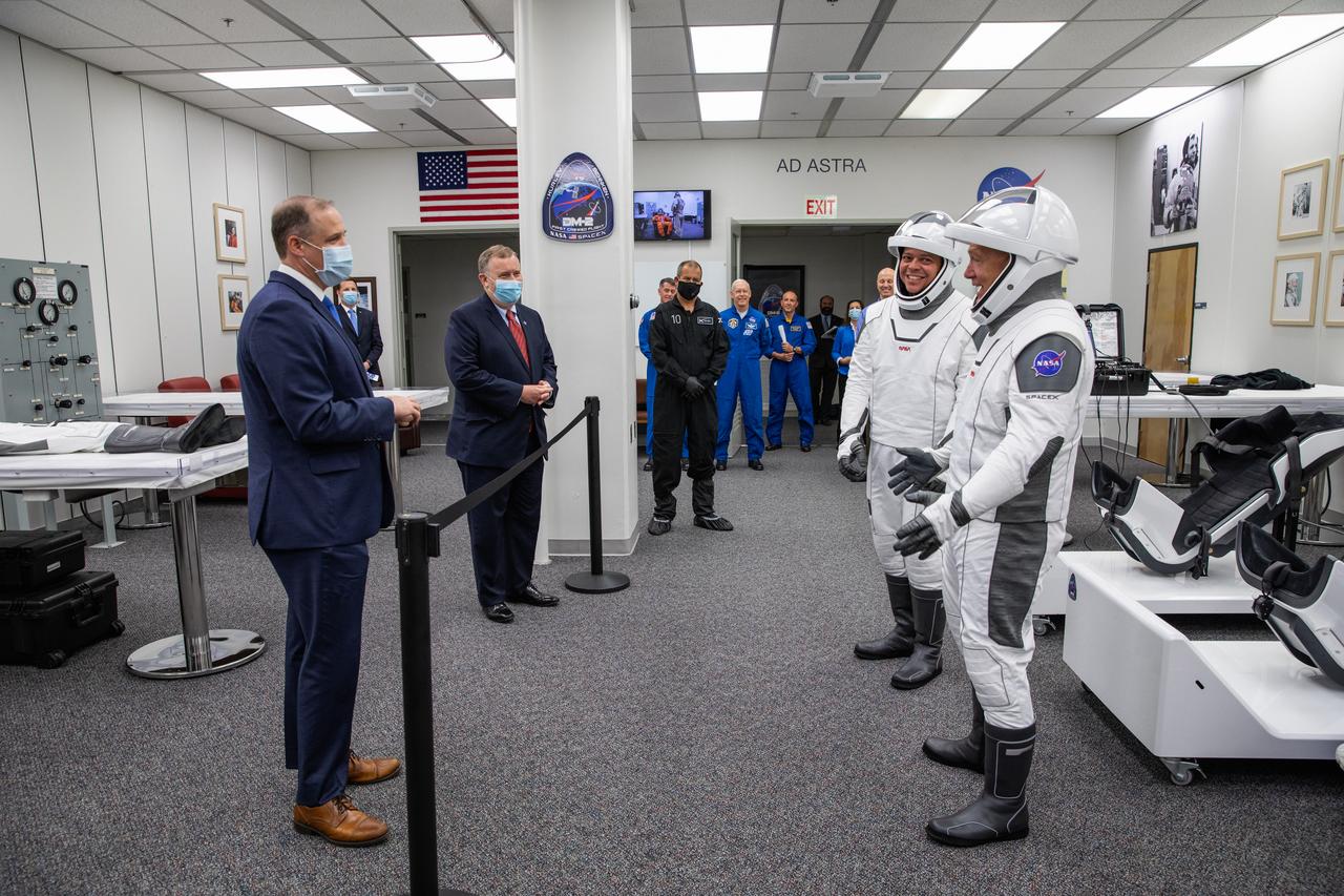 Behind the rope, NASA Administrator Jim Bridenstine (left) and Deputy Administrator Jim Morhard greet NASA astronauts Robert Behnken (left) and Douglas Hurley inside the Astronaut Crew Quarters in the Neil A. Armstrong Operations and Checkout Building at NASA’s Kennedy Space Center in Florida on May 30, 2020, ahead of the agency’s SpaceX Demo-2 mission. The SpaceX Falcon 9 rocket and Crew Dragon spacecraft lifted off at 3:22 p.m. EDT from historic Launch Complex 39A. Behnken and Hurley are the first astronauts to launch to the International Space Station from U.S. soil since the end of the Space Shuttle Program in 2011. Part of NASA’s Commercial Crew Program, this will be SpaceX’s final flight test, paving the way for the agency to certify the crew transportation system for regular, crewed flights to the orbiting laboratory.