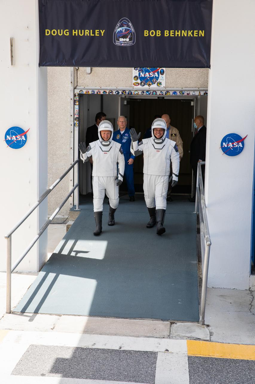 NASA astronauts Douglas Hurley (left) and Robert Behnken wave as they exit the Neil A. Armstrong Operations and Checkout Building at the agency’s Kennedy Space Center in Florida on May 30, 2020, in preparation for transport to Launch Complex 39A ahead of embarking on NASA’s SpaceX Demo-2 mission. The SpaceX Falcon 9 rocket and Crew Dragon spacecraft lifted off at 3:22 p.m. EDT. Behnken and Hurley are the first astronauts to launch to the International Space Station from U.S. soil since the end of the Space Shuttle Program in 2011. Part of NASA’s Commercial Crew Program, this will be SpaceX’s final flight test, paving the way for the agency to certify the crew transportation system for regular, crewed flights to the orbiting laboratory.