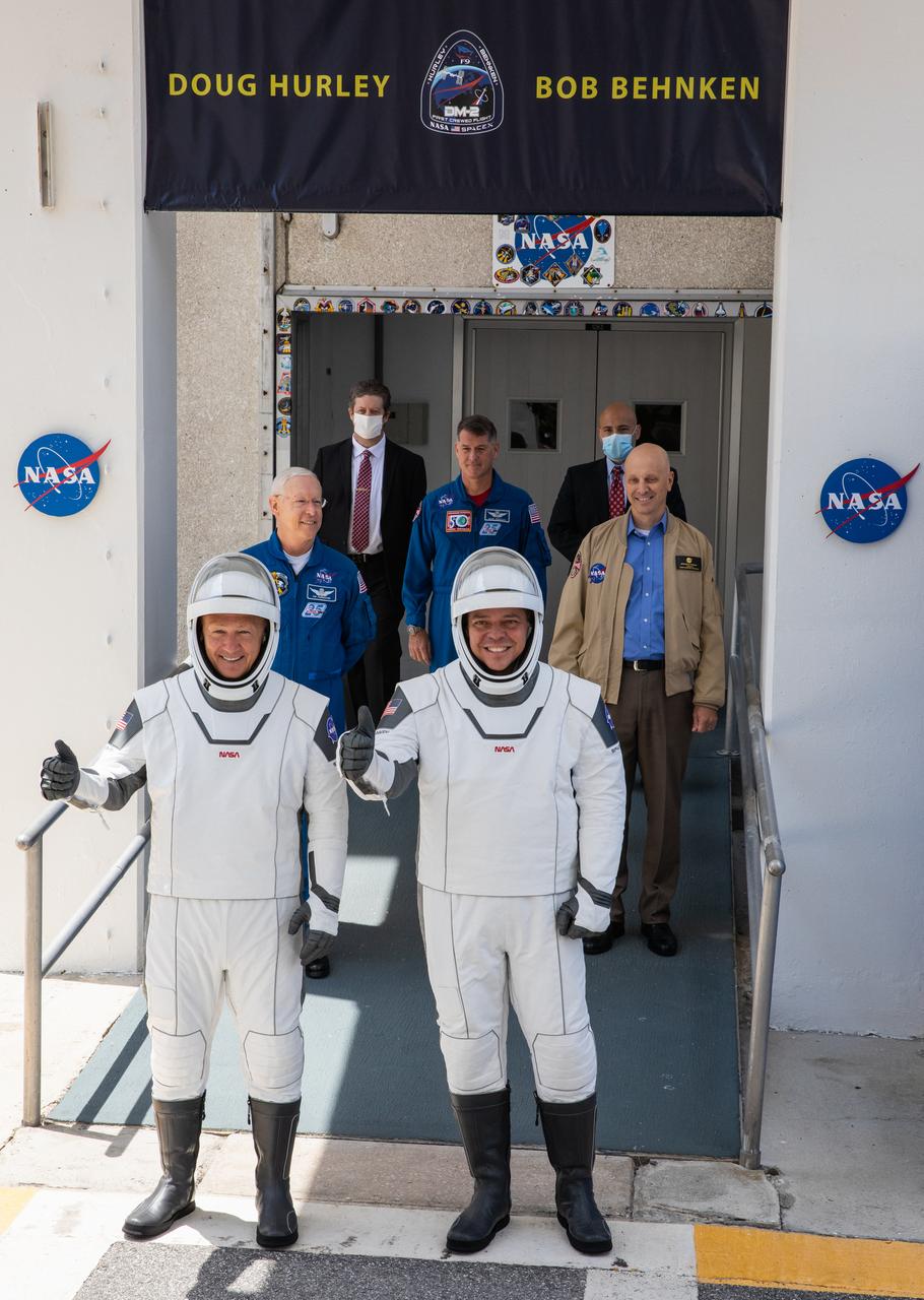 NASA astronauts Douglas Hurley (left) and Robert Behnken pause for a photo as they exit the Neil A. Armstrong Operations and Checkout Building at the agency’s Kennedy Space Center in Florida on May 30, 2020, in preparation for transport to Launch Complex 39A ahead of embarking on NASA’s SpaceX Demo-2 mission. The SpaceX Falcon 9 rocket and Crew Dragon spacecraft lifted off at 3:22 p.m. EDT. Behnken and Hurley are the first astronauts to launch to the International Space Station from U.S. soil since the end of the Space Shuttle Program in 2011. Part of NASA’s Commercial Crew Program, this will be SpaceX’s final flight test, paving the way for the agency to certify the crew transportation system for regular, crewed flights to the orbiting laboratory.