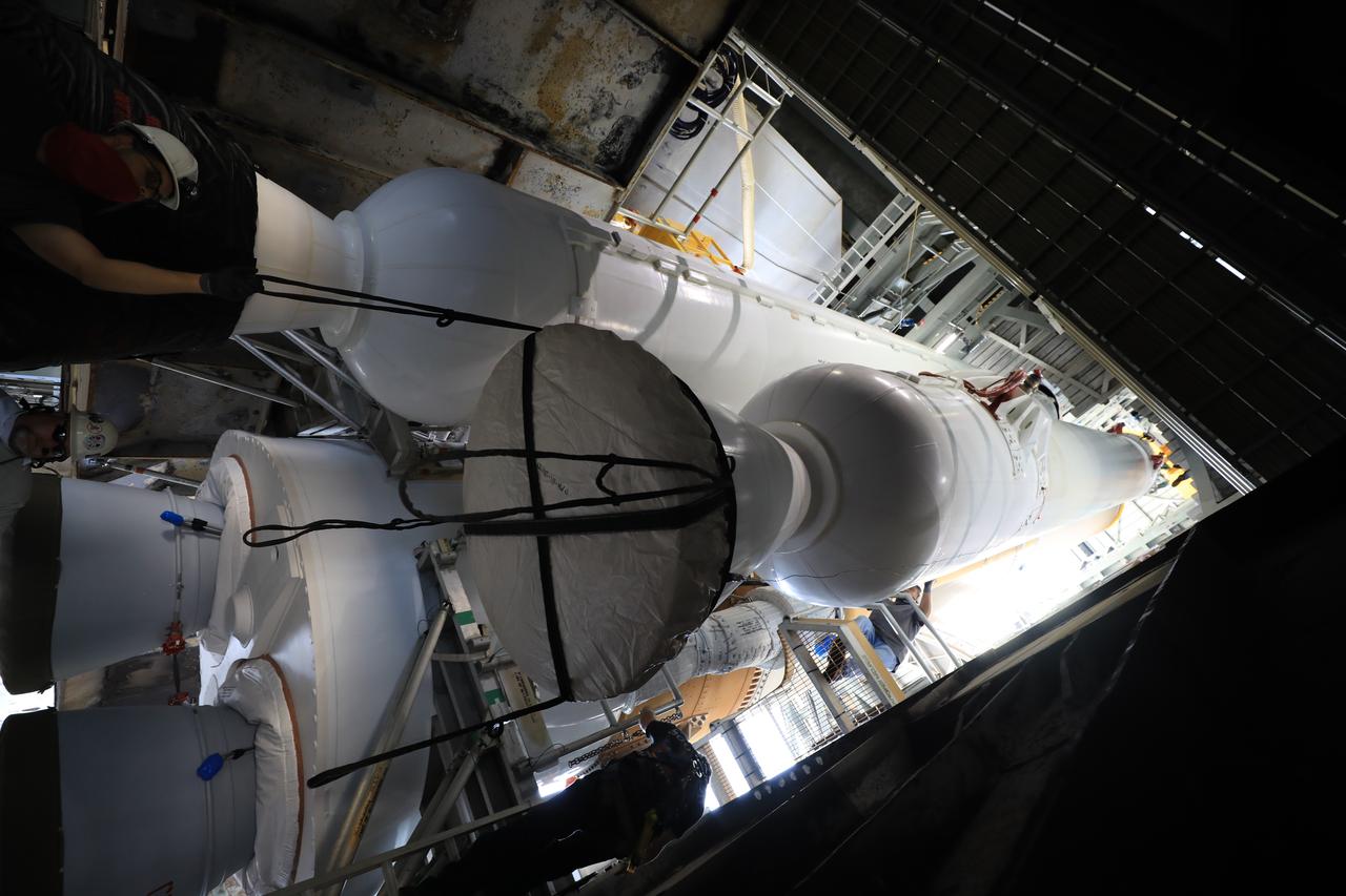 In this view looking up inside the Vertical Integration Facility at Space Launch Complex 41 at Cape Canaveral Air Force Station in Florida, the third of four solid rocket boosters (SRB) for the United Launch Alliance Atlas V 541 rocket is lowered by crane into position on June 8, 2020. The SRB will be mated to the Atlas V booster. NASA’s Mars 2020 mission with the Perseverance rover is scheduled to launch on July 20, 2020, atop the Atlas V rocket from Pad 41. The rover is part of NASA’s Mars Exploration Program, a long-term effort of robotic exploration of the Red Planet. The rover’s seven instruments will search for habitable conditions in the ancient past and signs of past microbial life on Mars. The Launch Services Program at Kennedy is responsible for launch management.