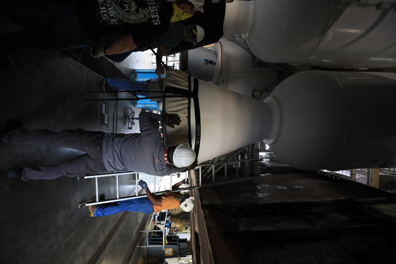 United Launch Alliance (ULA) workers assist as the third of four solid rocket boosters (SRB) for the ULA Atlas V 541 rocket is lowered by crane into position inside the Vertical Integration Facility at Space Launch Complex 41 at Cape Canaveral Air Force Station in Florida on June 8, 2020. The SRB will be mated to the Atlas V booster. NASA’s Mars 2020 mission with the Perseverance rover is scheduled to launch on July 20, 2020, atop the Atlas V rocket from Pad 41. The rover is part of NASA’s Mars Exploration Program, a long-term effort of robotic exploration of the Red Planet. The rover’s seven instruments will search for habitable conditions in the ancient past and signs of past microbial life on Mars. The Launch Services Program at Kennedy is responsible for launch management.