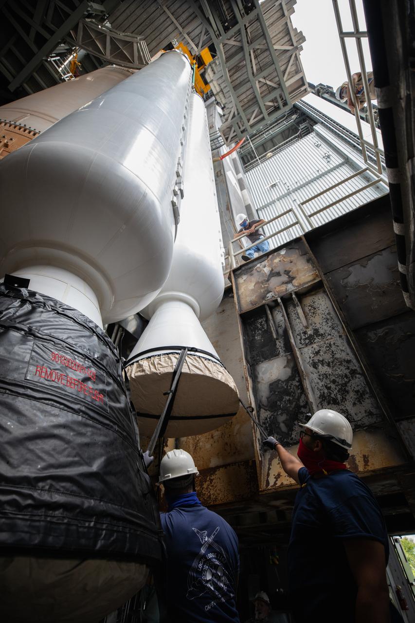 Inside the Vertical Integration Facility (VIF) at Space Launch Complex 41 at Cape Canaveral Air Force Station (CCAFS) in Florida, United Launch Alliance (ULA) workers watch as the fourth and final solid rocket booster (SRB) for the United Launch Alliance Atlas V 541 rocket is lowered by crane on June 9, 2020. The SRB will be mated to the Atlas V booster. NASA’s Mars 2020 mission with the Perseverance rover is scheduled to launch in July 2020, atop the Atlas V rocket from Pad 41. The rover is part of NASA’s Mars Exploration Program, a long-term effort of robotic exploration of the Red Planet. The rover’s seven instruments will search for habitable conditions in the ancient past and signs of past microbial life on Mars. The Launch Services Program at Kennedy is responsible for launch management.