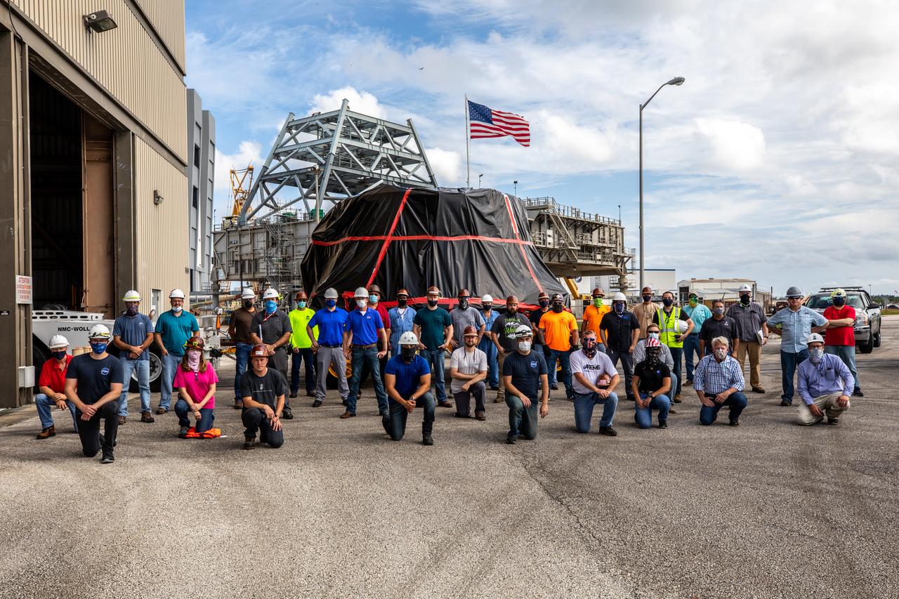 Exploration Ground Systems workers gather in front of the Rotation, Processing and Surge Facility (RPSF) at NASA’s Kennedy Space Center in Florida on June 10, 2020, to mark the arrival of the Artemis I aft skirts for the agency's Space Launch System (SLS) rocket’s twin solid rocket boosters. The aft skirts were moved from the Booster Fabrication Facility. The aft skirts were refurbished by Northrop Grumman. They house the thrust vector control system, which controls 70 percent of the steering during initial ascent of the SLS rocket. The segments will remain in the RPSF until ready for stacking with the forward and aft parts of the boosters on the mobile launcher in High Bay 3 of the Vehicle Assembly Building. Through the Artemis Program, NASA is working to land the first woman and next man on the Moon by 2024.