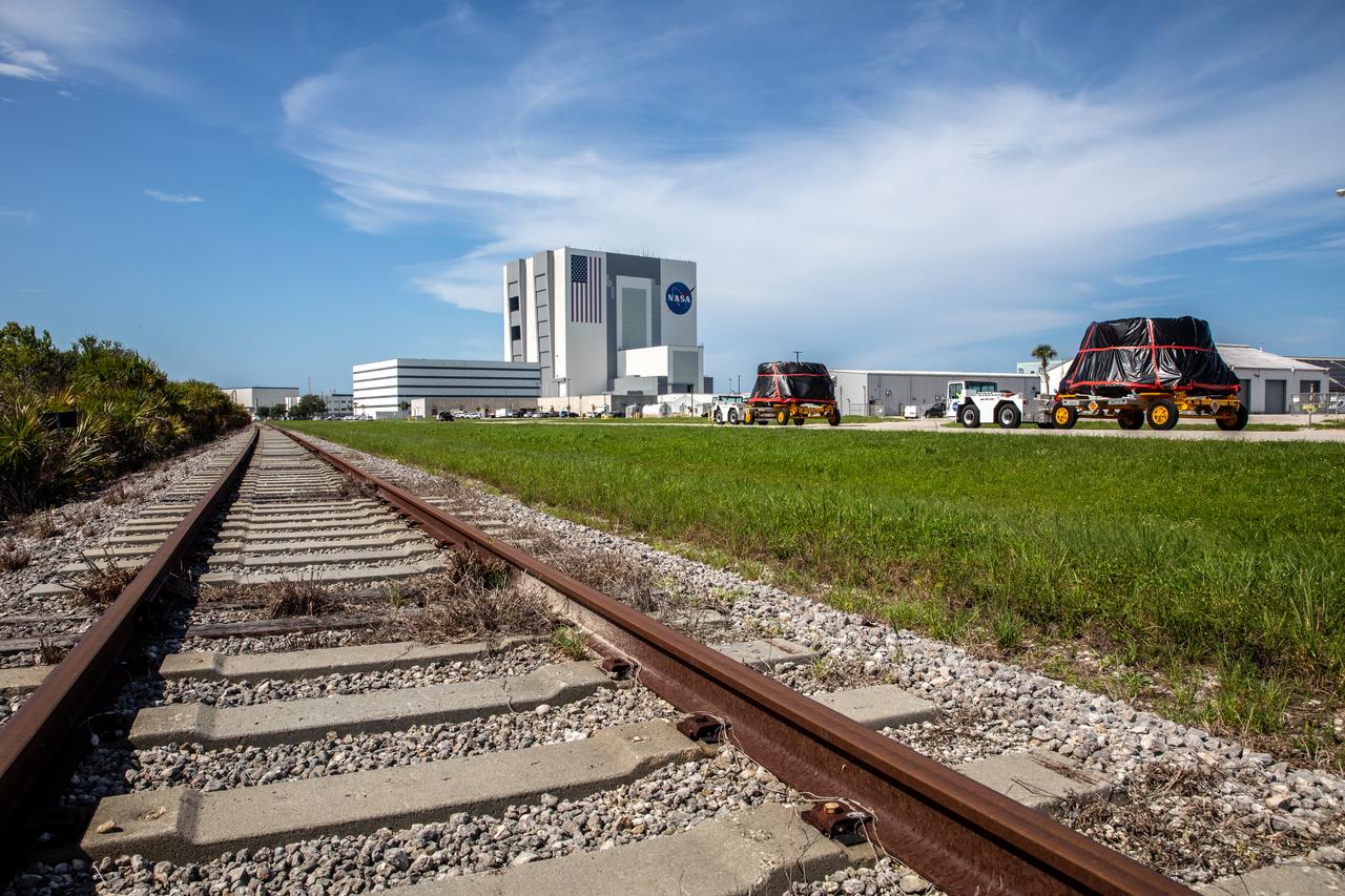 The Artemis I aft skirts for NASA’s Space Launch System (SLS) rocket’s twin solid rocket boosters are moved along the road to the Rotation, Processing and Surge Facility (RPSF) at the agency’s Kennedy Space Center in Florida on June 10, 2020. The aft skirts were refurbished by Northrop Grumman. They house the thrust vector control system, which controls 70 percent of the steering during initial ascent of the SLS rocket. The aft skirts will remain in the RPSF until ready for stacking with the forward and aft parts of the boosters on the mobile launcher in High Bay 3 of the Vehicle Assembly Building. Through the Artemis Program, NASA is working to land the first woman and next man on the Moon by 2024.