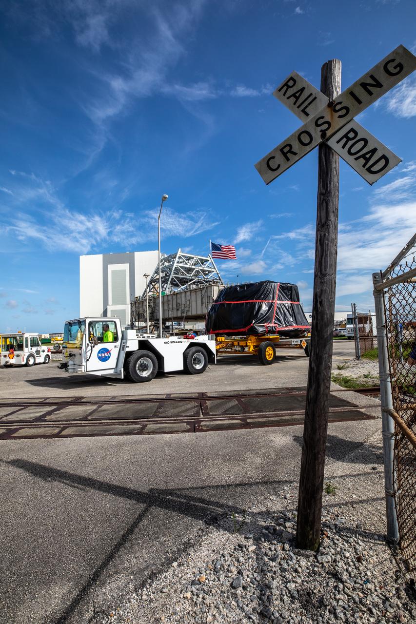One of two Artemis I aft skirts for NASA’s Space Launch System (SLS) rocket’s twin solid rocket boosters crosses a railroad track on its way to the Rotation, Processing and Surge Facility (RPSF) at the agency’s Kennedy Space Center in Florida on June 10, 2020. They were transported from the Booster Fabrication Facility. The aft skirts were refurbished by Northrop Grumman. They house the thrust vector control system, which controls 70 percent of the steering during initial ascent of the SLS rocket. The segments will remain in the RPSF until ready for stacking with the forward and aft parts of the boosters on the mobile launcher in High Bay 3 of the Vehicle Assembly Building. Through the Artemis Program, NASA is working to land the first woman and next man on the Moon by 2024.