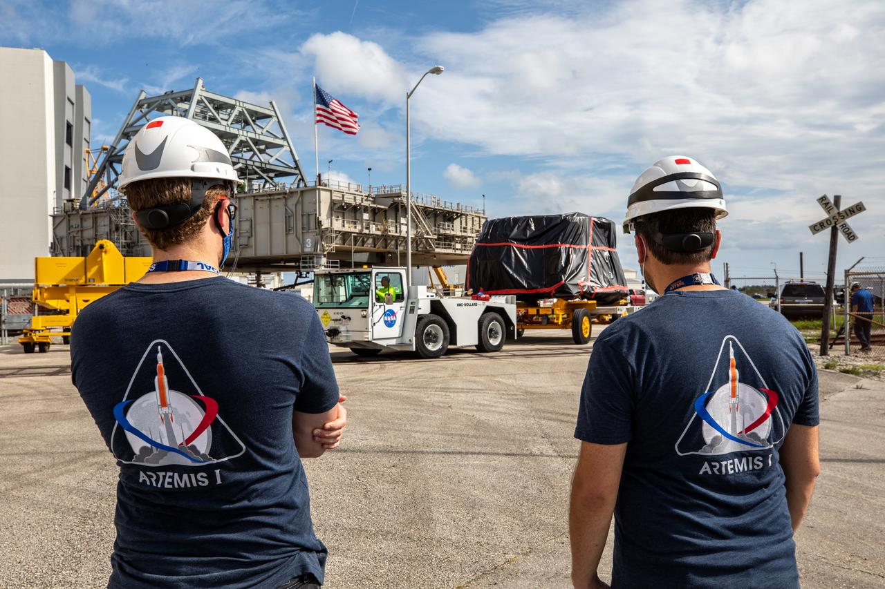 Exploration Ground Systems workers watch as the first of two Artemis I aft skirts for NASA’s Space Launch System (SLS) rocket’s twin solid rocket boosters crosses a railroad track on its way to the Rotation, Processing and Surge Facility (RPSF) at the agency’s Kennedy Space Center in Florida on June 10, 2020. They were transported from the Booster Fabrication Facility. The aft skirts were refurbished by Northrop Grumman. They house the thrust vector control system, which controls 70 percent of the steering during initial ascent of the SLS rocket. The segments will remain in the RPSF until ready for stacking with the forward and aft parts of the boosters on the mobile launcher in High Bay 3 of the Vehicle Assembly Building. Through the Artemis Program, NASA is working to land the first woman and next man on the Moon by 2024. 