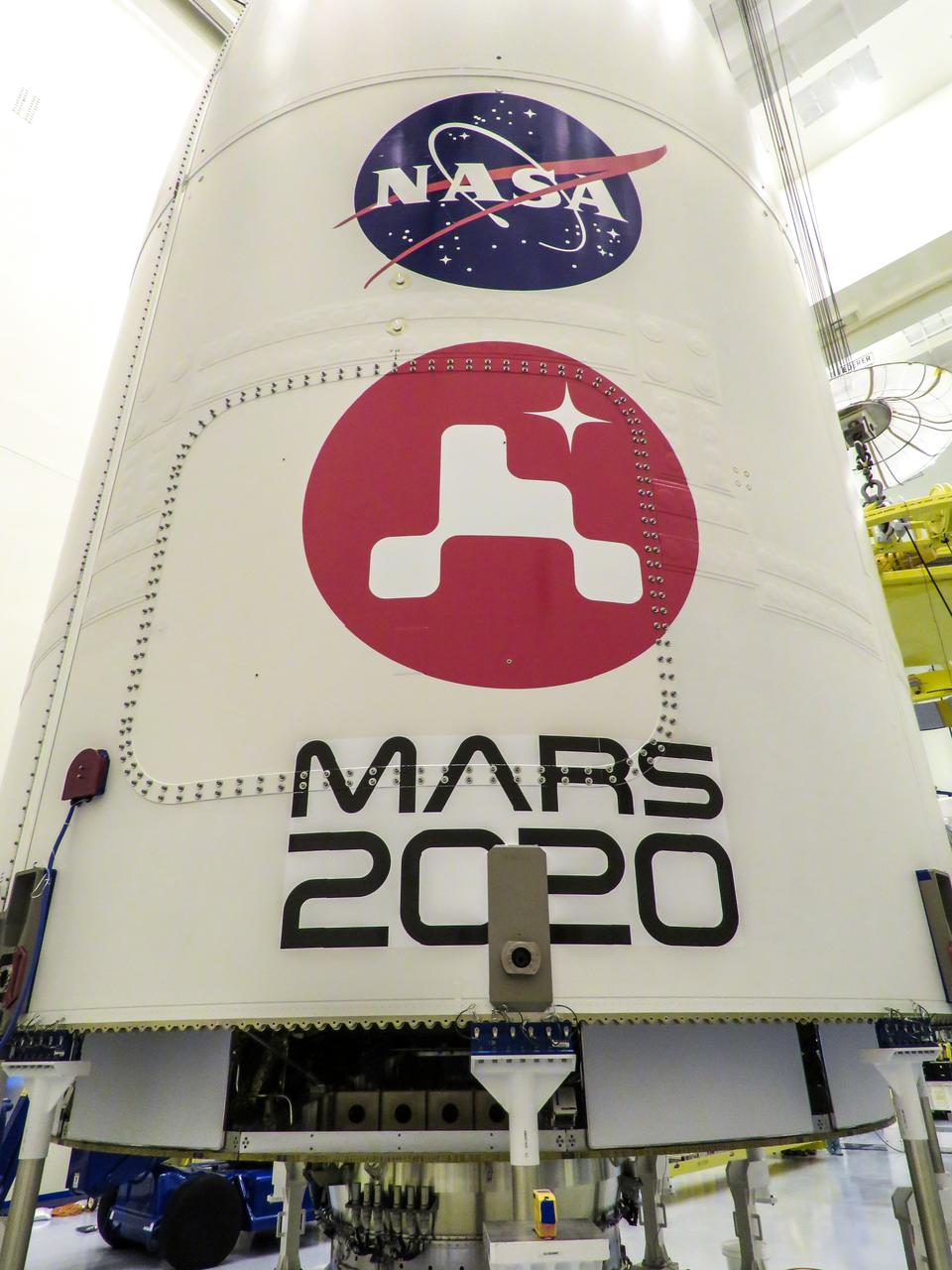 Inside the Payload Hazardous Servicing Facility at NASA’s Kennedy Space Center in Florida, the Mars 2020 logo is installed on the United Launch Alliance Atlas V payload fairing on June 18, 2020. Secured inside the fairing is the agency’s Mars 2020 Perseverance rover. The rover is scheduled to launch on July 20, 2020, atop the Atlas V 541 rocket from Space Launch Complex 41 at Cape Canaveral Air Force Station. The rover is part of NASA’s Mars Exploration Program, a long-term effort of robotic exploration of the Red Planet. The rover’s seven instruments will search for habitable conditions in the ancient past and signs of past microbial life on Mars. The Launch Services Program at Kennedy is responsible for launch management.