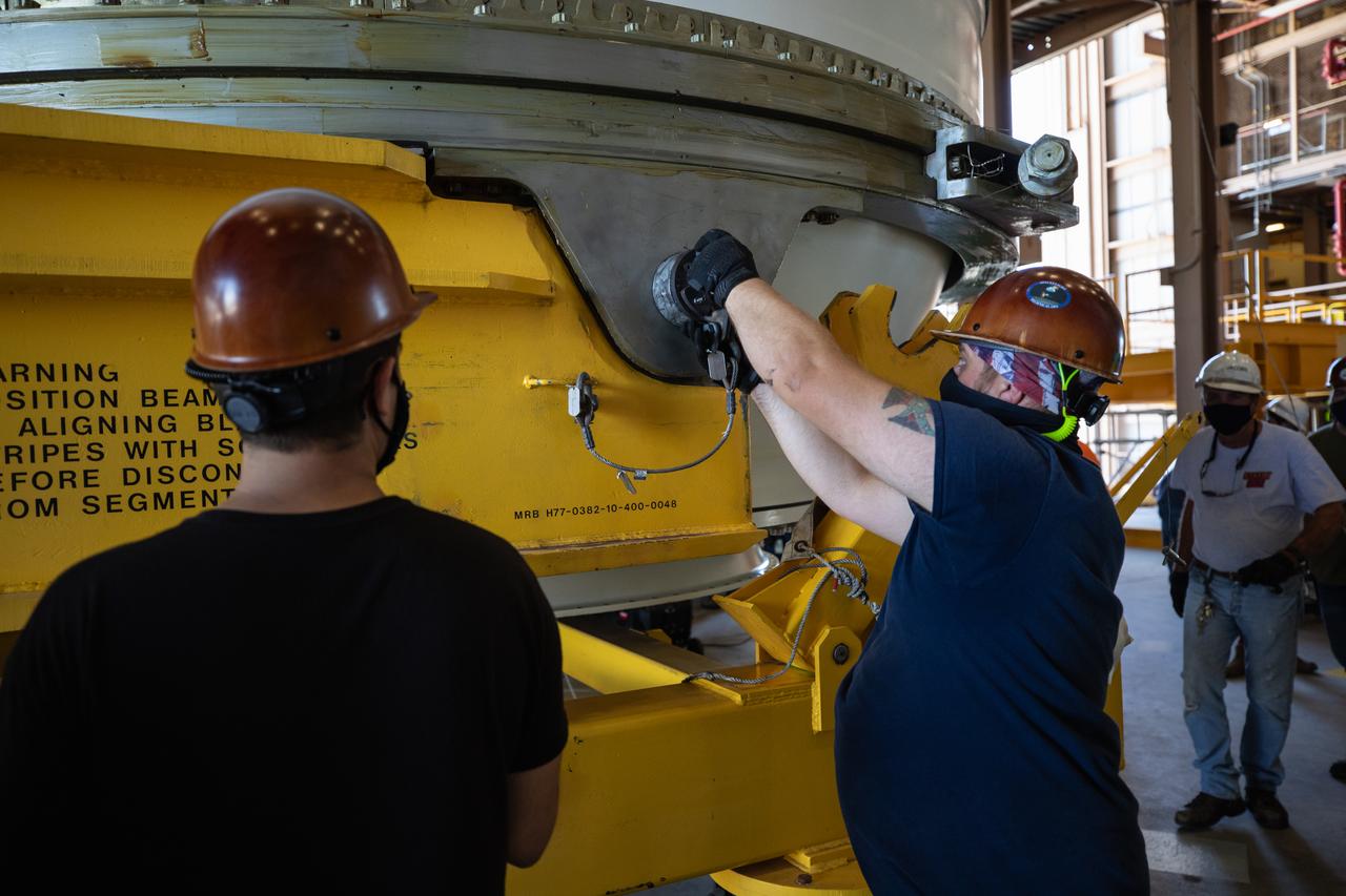 Inside the Rotation, Processing and Surge Facility (RPSF) at NASA’s Kennedy Space Center in Florida, technicians lift the right aft motor segment – one of five segments that make up one of two solid rocket boosters for the agency’s Space Launch System (SLS) – onto an inspection stand on June 23, 2020. While in the RPSF, the boosters will be mated to the rocket’s two aft skirts before they are moved to the Vehicle Assembly Building for stacking on the mobile launcher. The boosters, manufactured by Northrop Grumman in Utah, recently arrived at Kennedy for processing ahead of the Artemis I launch. Together, the twin boosters provide more than 75 percent of the total SLS thrust at launch. The first in a series of increasingly complex missions, Artemis I will test the Orion spacecraft and SLS as an integrated system ahead of crewed flights to the Moon.  