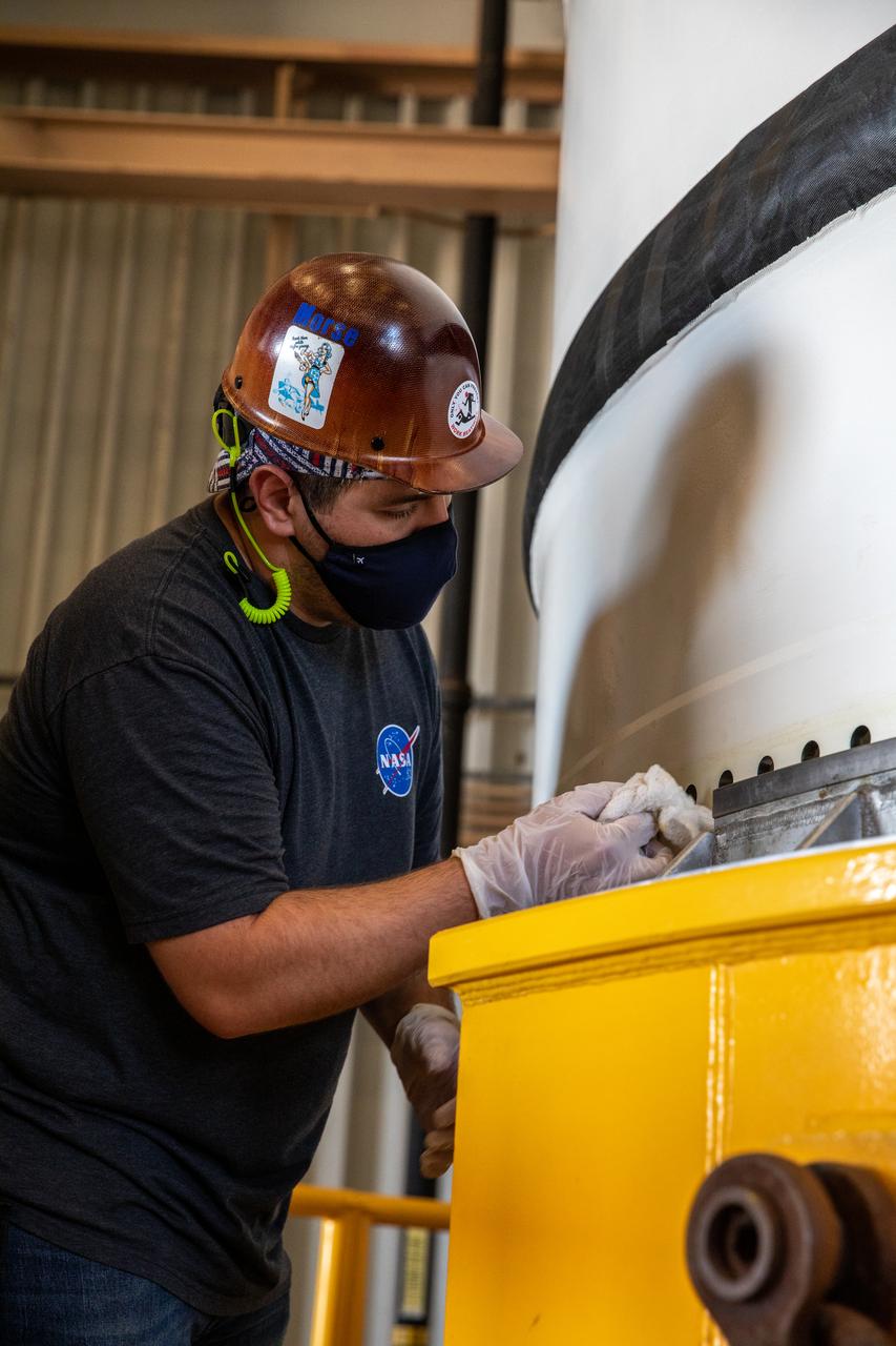 Inside the Rotation, Processing and Surge Facility at NASA’s Kennedy Space Center in Florida, a technician inspects and removes grease from the right-hand motor segment – one of five segments that make up one of two solid rocket boosters for the agency’s Space Launch System (SLS) – in preparation for mating to the rocket’s right-hand aft skirt on June 24, 2020. Once the booster aft segments are mated to the two aft skirts, they will be moved to the Vehicle Assembly Building for stacking on the mobile launcher. Manufactured by Northrop Grumman in Utah, the twin boosters provide more than 75 percent of the total SLS thrust at launch. Under the Artemis program, NASA will land the first woman and the next man on the Moon by 2024. The first in a series of increasingly complex missions, Artemis I will test the Orion spacecraft and SLS as an integrated system ahead of crewed flights to the Moon.