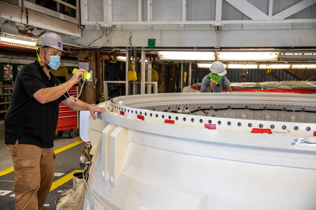 Brendan Deuble, a handling, mechanical and structures engineer on the Jacobs Technology Inc. Test and Operations Support Contract, inspects the Space Launch System’s (SLS) right-hand aft skirt inside the Rotation, Processing and Surge Facility (RPSF) at NASA’s Kennedy Space Center in Florida on June 24, 2020. While in the RPSF, the aft skirt will be mated with the rocket’s right-hand motor segment – one of five segments that make up one of two solid rocket boosters. Once the two aft skirts are mated with the aft segments, they will be moved to the Vehicle Assembly Building for stacking on the mobile launcher. Manufactured by Northrop Grumman in Utah, the twin boosters provide more than 75 percent of the total SLS thrust at launch. Under the Artemis program, NASA will land the first woman and the next man on the Moon by 2024. The first in a series of increasingly complex missions, Artemis I will test the Orion spacecraft and SLS as an integrated system ahead of crewed flights to the Moon.  