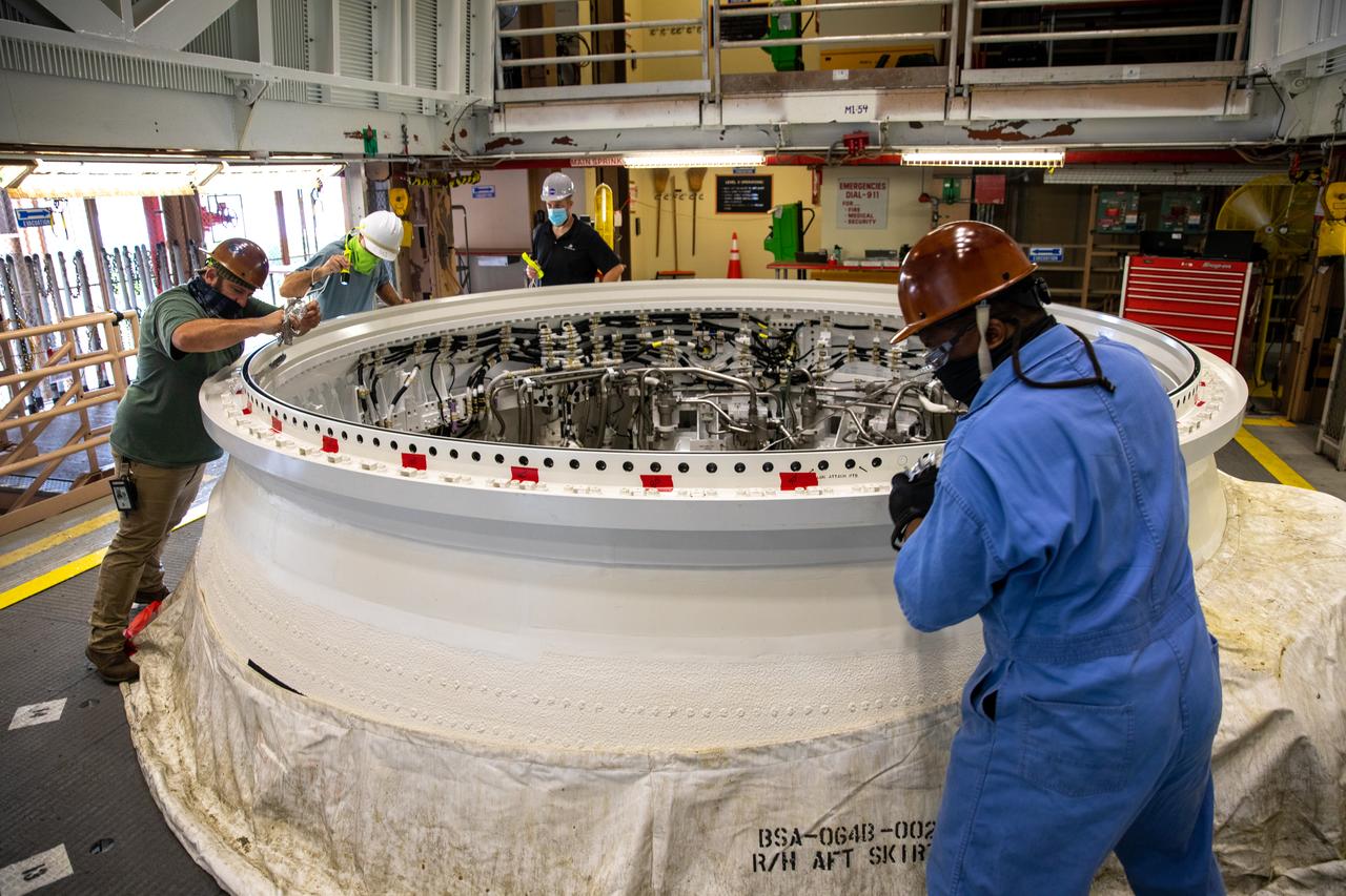Inside the Rotation, Processing and Surge Facility at NASA’s Kennedy Space Center in Florida, technicians inspect the Space Launch System’s (SLS) right-hand aft skirt prior to mating it with the rocket’s right-hand motor segment – one of five segments that make up one of two solid rocket boosters – on June 24, 2020. Once the two aft skirts are mated to the aft segments, they will be moved to the Vehicle Assembly Building for stacking on the mobile launcher. Manufactured by Northrop Grumman in Utah, the twin boosters provide more than 75 percent of the total SLS thrust at launch. Under the Artemis program, NASA will land the first woman and the next man on the Moon by 2024. The first in a series of increasingly complex missions, Artemis I will test the Orion spacecraft and SLS as an integrated system ahead of crewed flights to the Moon.