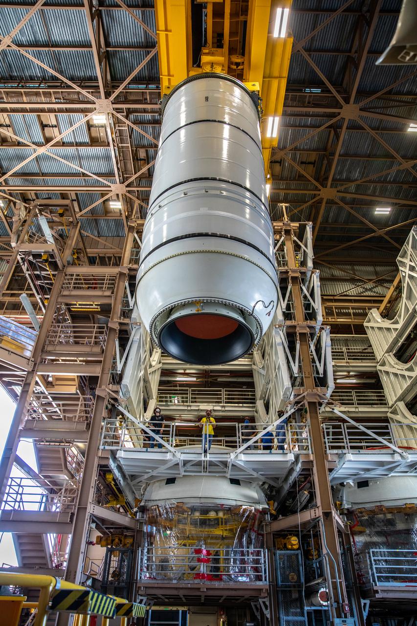 Inside the Rotation, Processing and Surge Facility at NASA’s Kennedy Space Center in Florida, technicians begin to mate the right-hand motor segment – one of five segments that make up one of two solid rocket boosters for the agency’s Space Launch System (SLS) – to the rocket’s right-hand aft skirt on June 24, 2020. Once the aft segments are mated to the two aft skirts, they will be moved to the Vehicle Assembly Building for stacking on the mobile launcher. Manufactured by Northrop Grumman in Utah, the twin boosters provide more than 75 percent of the total SLS thrust at launch. Under the Artemis program, NASA will land the first woman and the next man on the Moon by 2024. The first in a series of increasingly complex missions, Artemis I will test the Orion spacecraft and SLS as an integrated system ahead of crewed flights to the Moon.  
