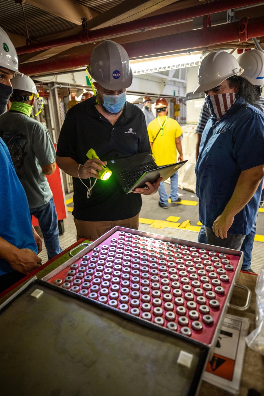 Inside the Rotation, Processing and Surge Facility at NASA’s Kennedy Space Center in Florida, technicians inspect the pins that will be used to secure the right-hand motor segment – one of five segments that make up one of two solid rocket boosters for the agency’s Space Launch System (SLS) – to the right-hand aft skirt on June 24, 2020. Once the aft segments are mated to the two aft skirts, they will be moved to the Vehicle Assembly Building for stacking on the mobile launcher. Manufactured by Northrop Grumman in Utah, the twin boosters provide more than 75 percent of the total SLS thrust at launch. Under the Artemis program, NASA will land the first woman and the next man on the Moon by 2024. The first in a series of increasingly complex missions, Artemis I will test the Orion spacecraft and SLS as an integrated system ahead of crewed flights to the Moon.