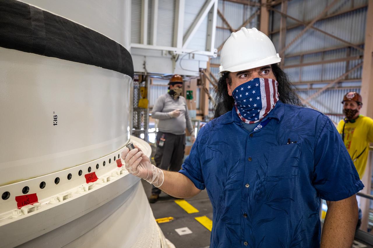 Inside the Rotation, Processing and Surge Facility at NASA’s Kennedy Space Center in Florida, Pablo Martinez, a handling, mechanical and structures engineer on the Jacobs Technology Inc. Test and Operations Support Contract, prepares to insert the first of many pins that will secure the Space Launch System’s (SLS) right-hand motor segment to the rocket’s right-hand aft skirt. The right-hand motor segment is one of five segments that makes up one of two solid rocket boosters. Once the aft segments are mated to the two aft skirts, they will be moved to the Vehicle Assembly Building for stacking on the mobile launcher. Manufactured by Northrop Grumman in Utah, the twin boosters provide more than 75 percent of the total SLS thrust at launch. Under the Artemis program, NASA will land the first woman and the next man on the Moon by 2024. The first in a series of increasingly complex missions, Artemis I will test the Orion spacecraft and SLS as an integrated system ahead of crewed flights to the Moon.