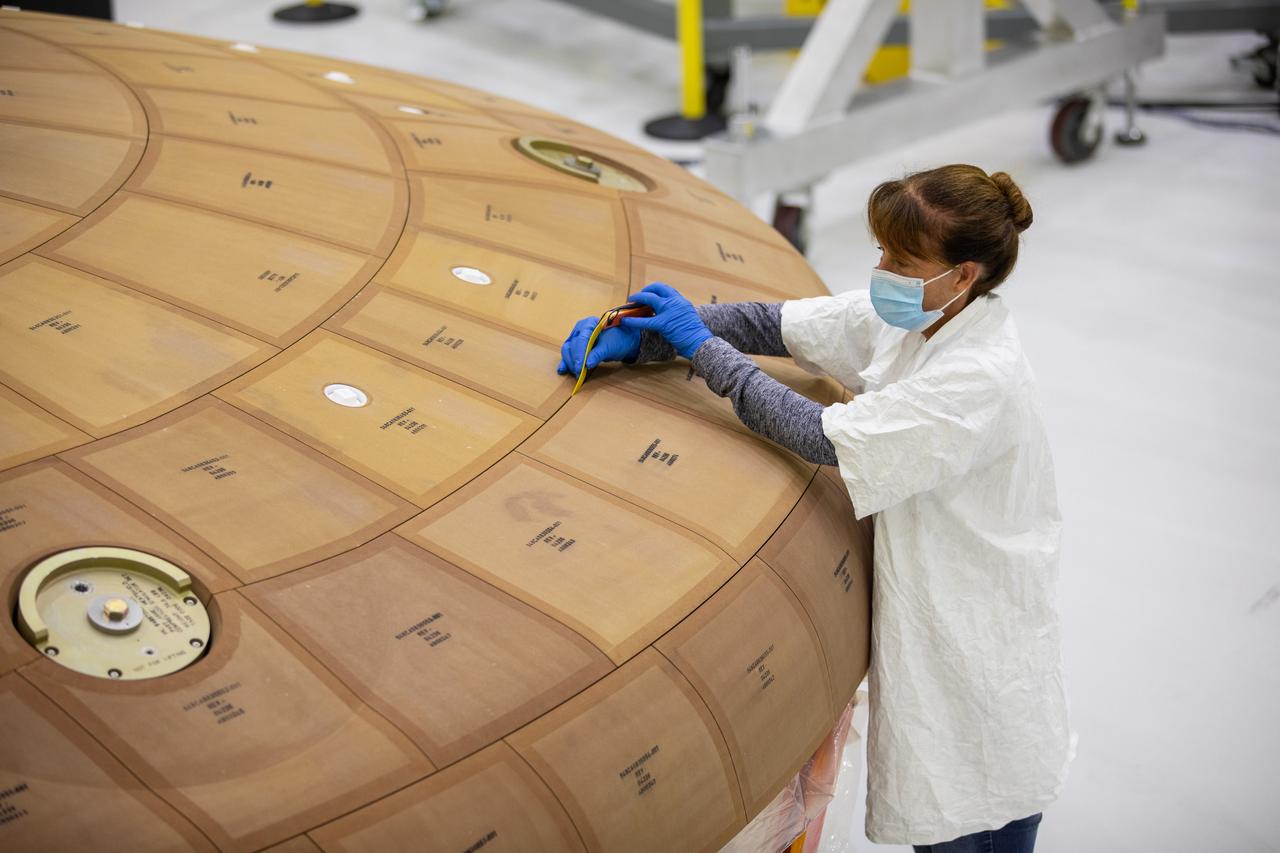 Inside the Neil Armstrong Operations and Checkout Building high bay at NASA's Kennedy Space Center in Florida, Darlene Beville with ASRC Federal, inspects AVOCAT block bonding on the Artemis II heat shield on July 2, 2020. The heat shield is one of the most critical elements of Orion and will protect the capsule and astronauts during reentry through Earth’s atmosphere. Artemis II is the first crewed mission in a series of missions to the Moon and on to Mars. Artemis II will confirm all of the Orion spacecraft’s systems operate as designed in the actual environment of deep space with astronauts aboard. As part of the Artemis Program, NASA will send the first woman and next man to the Moon by 2024.