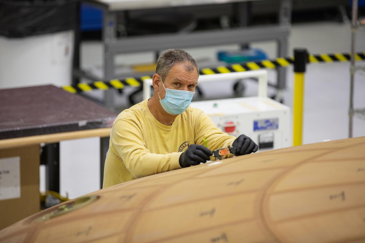 Inside the Neil Armstrong Operations and Checkout Building high bay at NASA's Kennedy Space Center in Florida, technician Kenny Leidner with ASRC Federal, inspects AVCOAT block bonding on the Artemis II heat shield on July 2, 2020. The heat shield is one of the most critical elements of Orion and will protect the capsule and astronauts during reentry through Earth’s atmosphere. Artemis II is the first crewed mission in a series of missions to the Moon and on to Mars. Artemis II will confirm all of the Orion spacecraft’s systems operate as designed in the actual environment of deep space with astronauts aboard. As part of the Artemis Program, NASA will send the first woman and next man to the Moon by 2024.