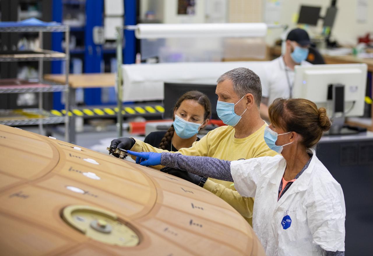 Inside the Neil Armstrong Operations and Checkout Building high bay at NASA's Kennedy Space Center in Florida, from left, technicians Diamond ScharSenstine, Kenny Leidner and Darlene Beville, all with ASRC Federal, inspect AVCOAT block bonding on the Artemis II heat shield on July 2, 2020. The heat shield is one of the most critical elements of Orion and will protect the capsule and astronauts during reentry through Earth’s atmosphere. Artemis II is the first crewed mission in a series of missions to the Moon and on to Mars. Artemis II will confirm all of the Orion spacecraft’s systems operate as designed in the actual environment of deep space with astronauts aboard. As part of the Artemis Program, NASA will send the first woman and next man to the Moon by 2024.