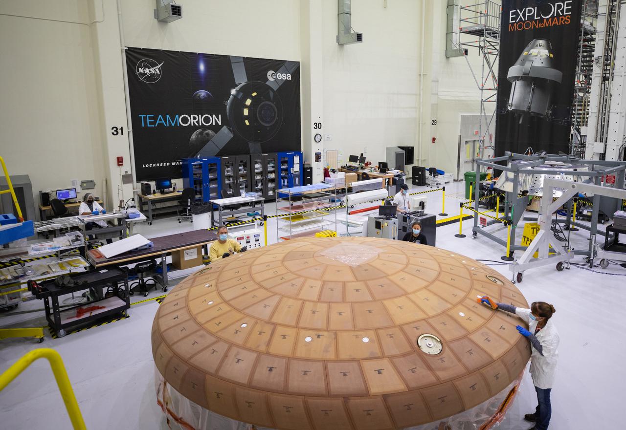 Inside the Neil Armstrong Operations and Checkout Building high bay at NASA's Kennedy Space Center in Florida, from left, technicians Kenny Leidner, Diamond ScharSenstine, Russ Novak and Darlene Beville with ASRC Federal, inspect AVCOAT block bonding on the Artemis II heat shield on July 2, 2020. The heat shield is one of the most critical elements of Orion and will protect the capsule and astronauts during reentry through Earth’s atmosphere. Artemis II is the first crewed mission in a series of missions to the Moon and on to Mars. Artemis II will confirm all of the Orion spacecraft’s systems operate as designed in the actual environment of deep space with astronauts aboard. As part of the Artemis Program, NASA will send the first woman and next man to the Moon by 2024.
