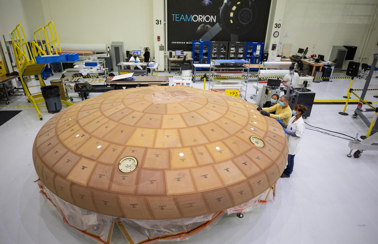 Inside the Neil Armstrong Operations and Checkout Building high bay at NASA's Kennedy Space Center in Florida, from left, technicians Diamond ScharSenstine, Kenny Leidner, Russ Novak and Darlene Beville, all with ASRC Federal, inspect AVCOAT block bonding on the Artemis II heat shield on July 2, 2020. The heat shield is one of the most critical elements of Orion and will protect the capsule and astronauts during reentry through Earth’s atmosphere. Artemis II is the first crewed mission in a series of missions to the Moon and on to Mars. Artemis II will confirm all of the Orion spacecraft’s systems operate as designed in the actual environment of deep space with astronauts aboard. As part of the Artemis Program, NASA will send the first woman and next man to the Moon by 2024.