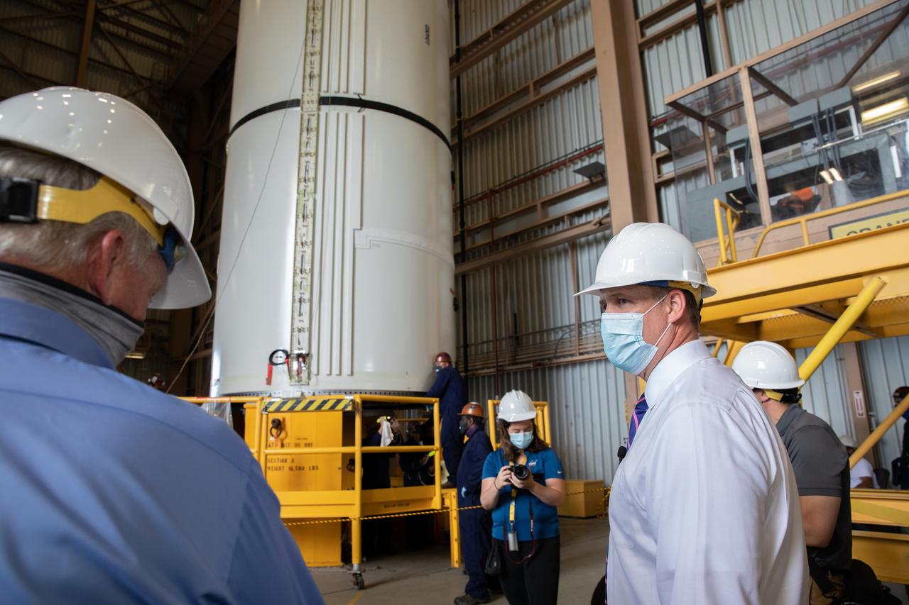 NASA Administrator Jim Bridenstine (right), accompanied by Jacobs employees, views Artemis I booster hardware inside the Rotation, Processing and Surge Facility at NASA’s Kennedy Space Center in Florida on July 27, 2020. Manufactured by Northrop Grumman in Utah, the boosters for the agency’s Space Launch System (SLS) rocket are now undergoing prelaunch processing at Kennedy. During launch, the twin boosters will provide more than 75 percent of the total SLS thrust. The first in a series of increasingly complex missions, Artemis I will test the Orion spacecraft and SLS as an integrated system ahead of crewed flights to the Moon.  
