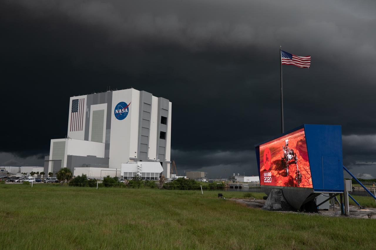 From NASA Kennedy Space Center’s Press Site lawn near the iconic countdown clock, storm clouds can be seen rolling in over the Vehicle Assembly Building (VAB) on July 28, 2020. Standing at 525 feet tall, this facility is capable of hosting multiple varieties of rockets and spacecraft at the same time. Currently, the VAB is being utilized to process and assemble the agency’s Space Launch System (SLS) rocket for Artemis missions to the Moon and beyond to Mars. Artemis I – the first launch under the agency’s Artemis Program – will test SLS and Orion as an integrated system prior to crewed flights to the Moon.
