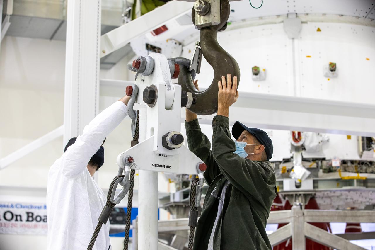 ASRC technicians Dustin Swickert, to the left. and John Nesbitt, to the right, work to attach the crane that lifts the Artemis I Orion spacecraft in preparation for installation of the spacecraft adapter (SA) cone inside the Neil Armstrong Operations and Checkout Building at NASA’s Kennedy Space Center in Florida on Aug. 6, 2020. This is one of the final major hardware operations the spacecraft will undergo during closeout processing prior to being integrated with the Space Launch System (SLS) rocket in preparation for the first Artemis mission. The spacecraft adapter cone connects the bottom portion of Orion’s service module to the top part of the rocket known as the interim cryogenic propulsion stage (ICPS). Orion will fly on the agency’s Artemis I mission – the first in a series of increasingly complex missions to the Moon that will ultimately lead to the exploration of Mars.