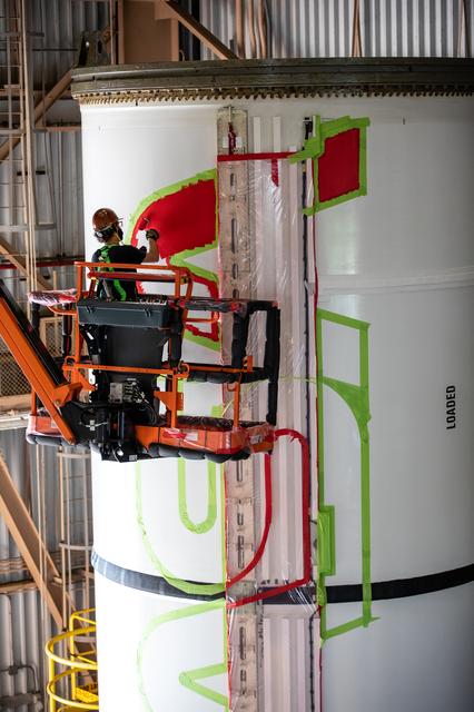 A worker with NASA’s Exploration Ground Systems (EGS) applies bright red pain...