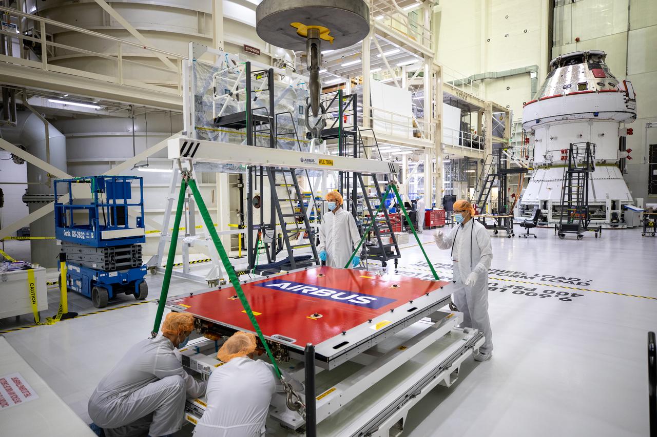 Technicians with European Service Module processing teams from the European Space Agency, Airbus, and Airbus Netherlands assist with securing a protective cover as a crane prepares to lift the panel during installation of one of four solar array wings inside the Neil Armstrong Operations and Checkout Building high bay at NASA’s Kennedy Space Center in Florida on Sept. 23, 2020. The Orion spacecraft for Artemis I is shown in the background. The solar arrays were extended, inspected, and then retracted, before installation on the spacecraft. Each solar array panel will generate 11 kilowatts of power and span about 63 feet. The array is a component of Orion’s service module, which is provided by the European Space Agency and built by Airbus Defence and Space to supply Orion’s power, propulsion, air and water. The first in a series of increasingly complex missions, Artemis I will test the Orion spacecraft and Space Launch System as an integrated system ahead of crewed flights to the Moon. Under the Artemis program, NASA will land the first woman and the next man on the Moon in 2024.