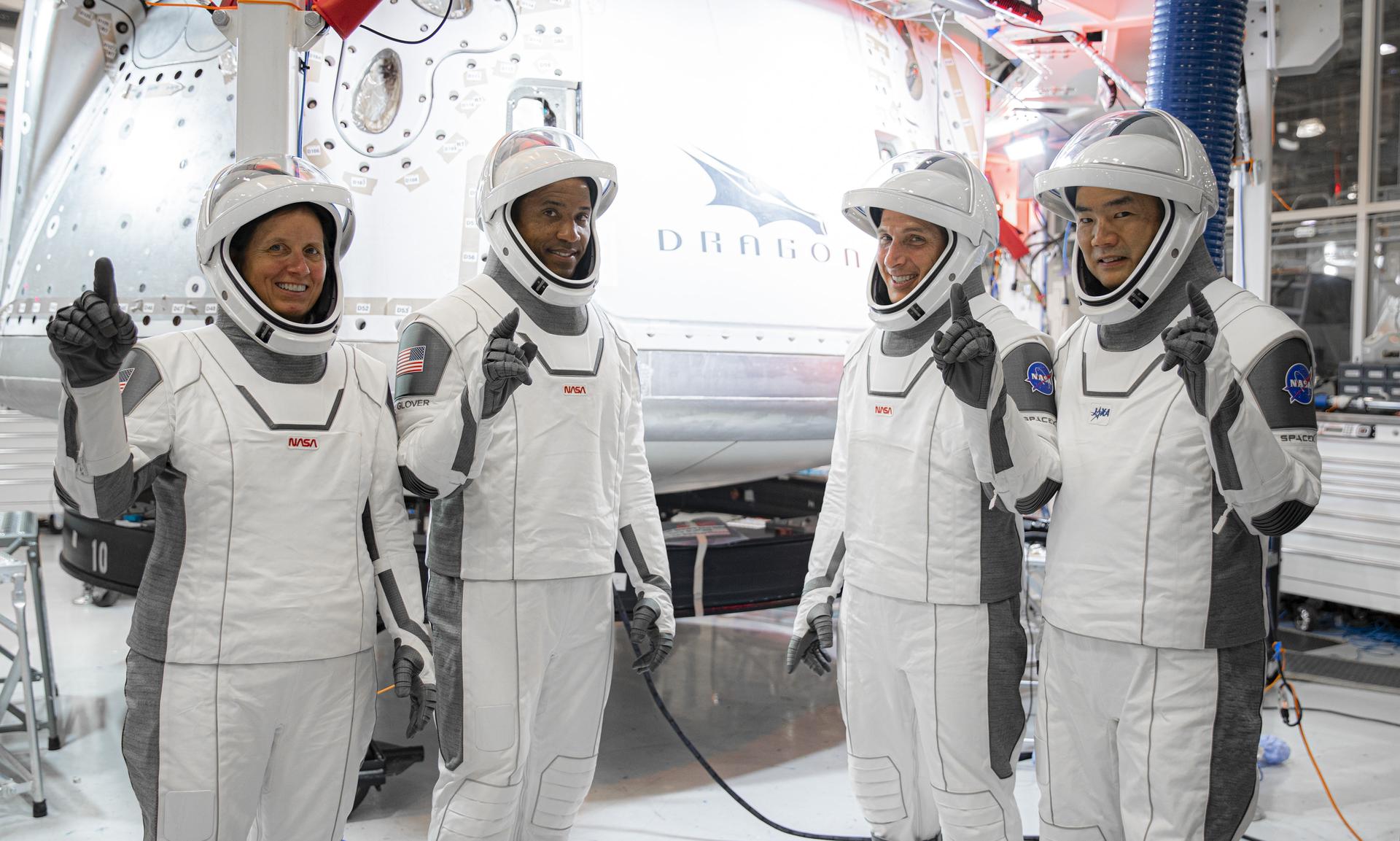 Image shows four astronauts in their suits giving a "thumbs up"