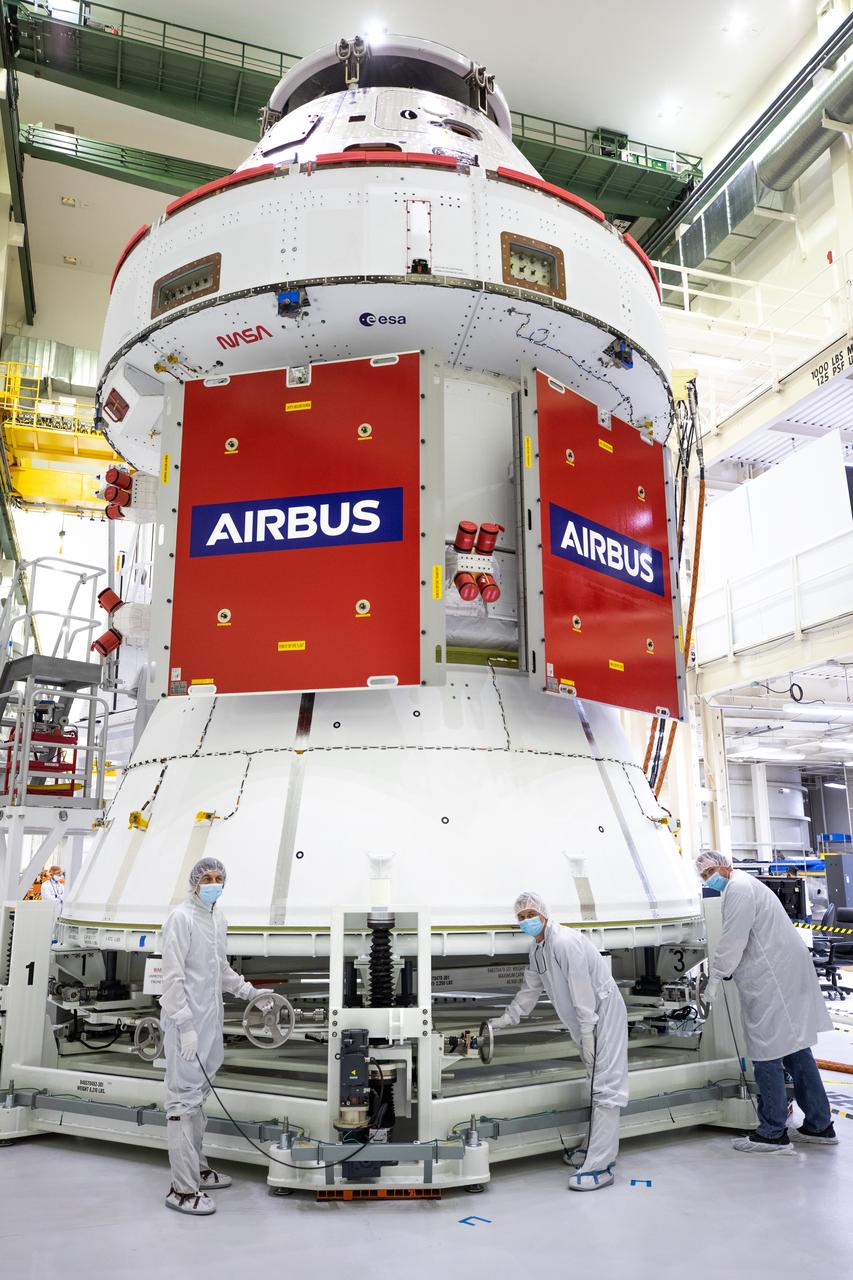 In view, protective covers have been placed over two solar array wings after they were installed on the Orion spacecraft for Artemis I inside the Neil Armstrong Operations and Checkout Building high bay at NASA’s Kennedy Space Center in Florida on Sept. 25, 2020. Standing in front of the spacecraft are technicians with ASRC. The solar arrays were extended, inspected, and then retracted before installation on the spacecraft. Each of the four solar array panels will generate 11 kilowatts of power and span about 63 feet. The array is a component of Orion’s service module, which is provided by the European Space Agency and built by Airbus Defence and Space to supply Orion’s power, propulsion, air, and water. The first in a series of increasingly complex missions, Artemis I will test the Orion spacecraft and Space Launch System as an integrated system ahead of crewed flights to the Moon. Under the Artemis program, NASA will land the first woman and the next man on the Moon in 2024.