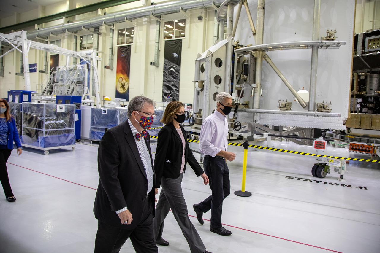 Catherine Koerner, in the center, NASA Orion Program manager, along with senior managers from Orion and Lockheed Martin, tours the Neil Armstrong Operations and Checkout Building at NASA’s Kennedy Space Center in Florida on Oct. 6, 2020. Accompanying her, at left is Mike Hawes, Lockheed Martin vice president and Orion Program manager; and at right is Scott Wilson, NASA Kennedy Orion Production Operations manager. Koerner viewed the Orion spacecraft for the Artemis I and II missions. They are shown with one of the space adapter jettison fairing panels that will be installed on Orion for the Artemis I mission. The first in a series of increasingly complex missions, Artemis I will test the Orion spacecraft and Space Launch System as an integrated system ahead of crewed flights to the Moon. Under the Artemis program, NASA will land the first woman and the next man on the Moon in 2024.