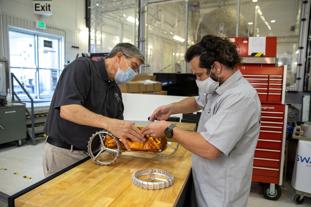 Jim Mantovani, left, and A.J. Nick, with Kennedy Space Center’s Exploration and Research and Technology programs, unbox a CubeRover at the Florida spaceport on Oct. 9, 2020. The rover was delivered by Pittsburgh-based space robotics company Astrobotic, as part of a Small Business Innovative Research (SBIR) award from NASA. Nick will lead CubeRover testing in the coming months in the Granular Mechanics and Regolith Operations (GMRO) Laboratory’s regolith bin, which holds approximately 120 tons of lunar regolith simulant at Kennedy’s Swamp Works. In 2019, NASA announced a $2 million Tipping Point award to develop more mature CubeRover’s payload interfaces and increase its capabilities.