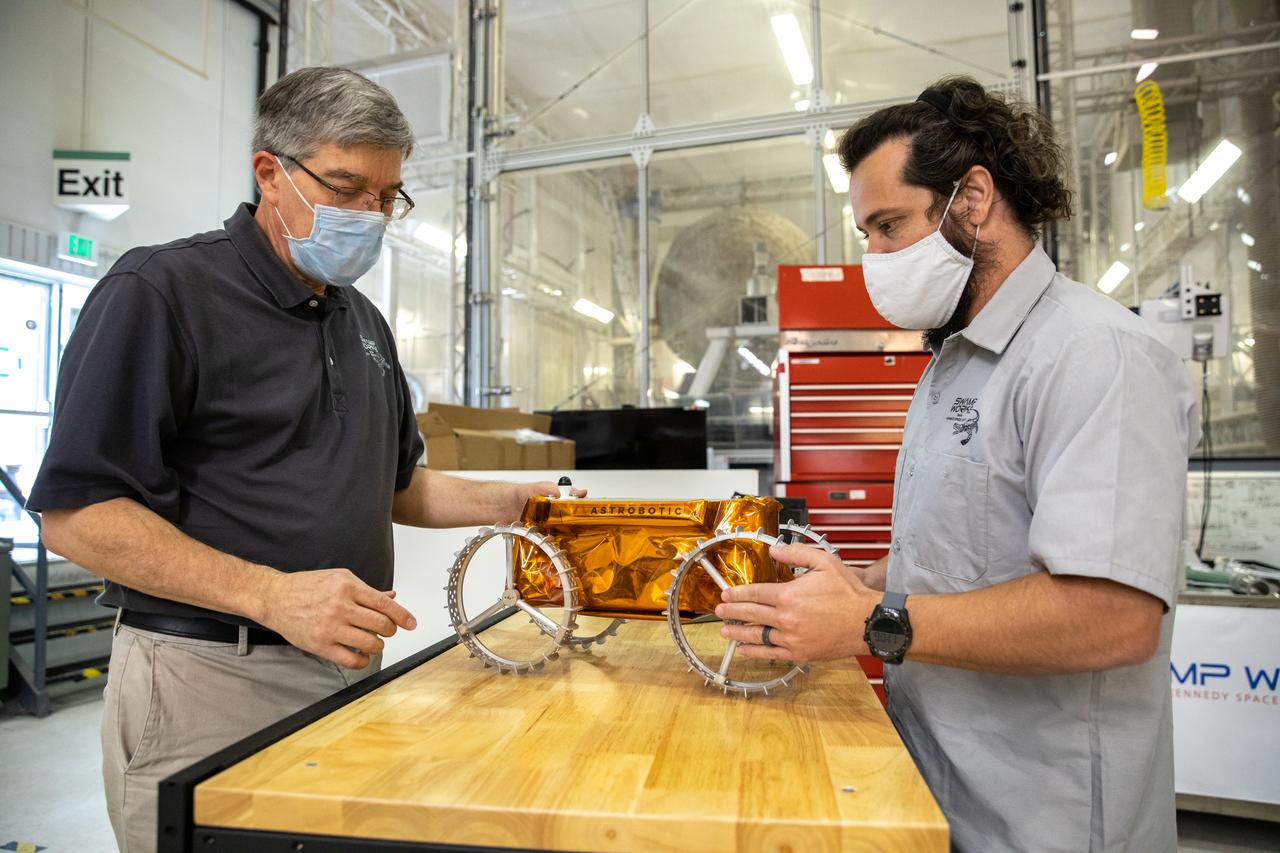 Jim Mantovani, left, and A.J. Nick, with Kennedy Space Center’s Exploration and Research and Technology programs, unbox a CubeRover at the Florida spaceport on Oct. 9, 2020. The rover was delivered by Pittsburgh-based space robotics company Astrobotic, as part of a Small Business Innovative Research (SBIR) award from NASA. Nick will lead CubeRover testing in the coming months in the Granular Mechanics and Regolith Operations (GMRO) Laboratory’s regolith bin, which holds approximately 120 tons of lunar regolith simulant at Kennedy’s Swamp Works. In 2019, NASA announced a $2 million Tipping Point award to develop more mature CubeRover’s payload interfaces and increase its capabilities.