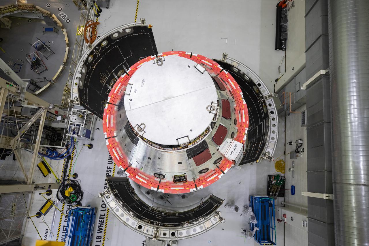 Shown is an overhead view of three spacecraft adapter jettison fairing panels fitted onto Orion’s European Service Module (ESM) on Oct. 13, 2020, inside the Neil Armstrong Operations and Checkout Building (O&C) at NASA’s Kennedy Space Center in Florida. The panels were inspected and moved into place for installation by technicians with Lockheed Martin. Recently, teams from across the globe installed the four solar array wings, which are housed inside the protective covering of the fairings. Once secured, they will encapsulate the ESM to protect it from harsh environments such as heat, wind, and acoustics as the spacecraft is propelled out of Earth’s atmosphere atop the Space Launch System (SLS) rocket during NASA’s Artemis I mission.
