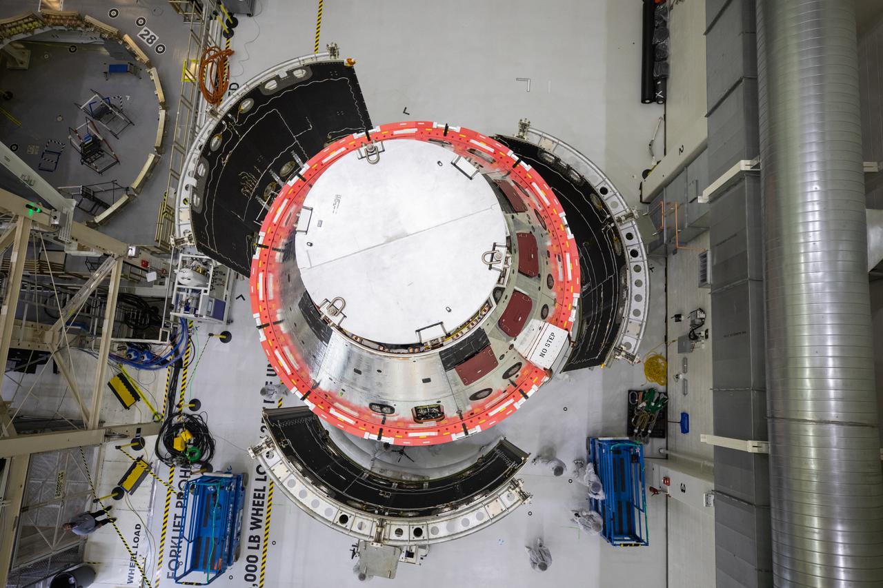 Shown is an overhead view of three spacecraft adapter jettison fairing panels fitted onto Orion’s European Service Module (ESM) on Oct. 13, 2020, inside the Neil Armstrong Operations and Checkout Building (O&C) at NASA’s Kennedy Space Center in Florida. The panels were inspected and moved into place for installation by technicians with Lockheed Martin. Recently, teams from across the globe installed the four solar array wings, which are housed inside the protective covering of the fairings. Once secured, they will encapsulate the ESM to protect it from harsh environments such as heat, wind, and acoustics as the spacecraft is propelled out of Earth’s atmosphere atop the Space Launch System (SLS) rocket during NASA’s Artemis I mission.