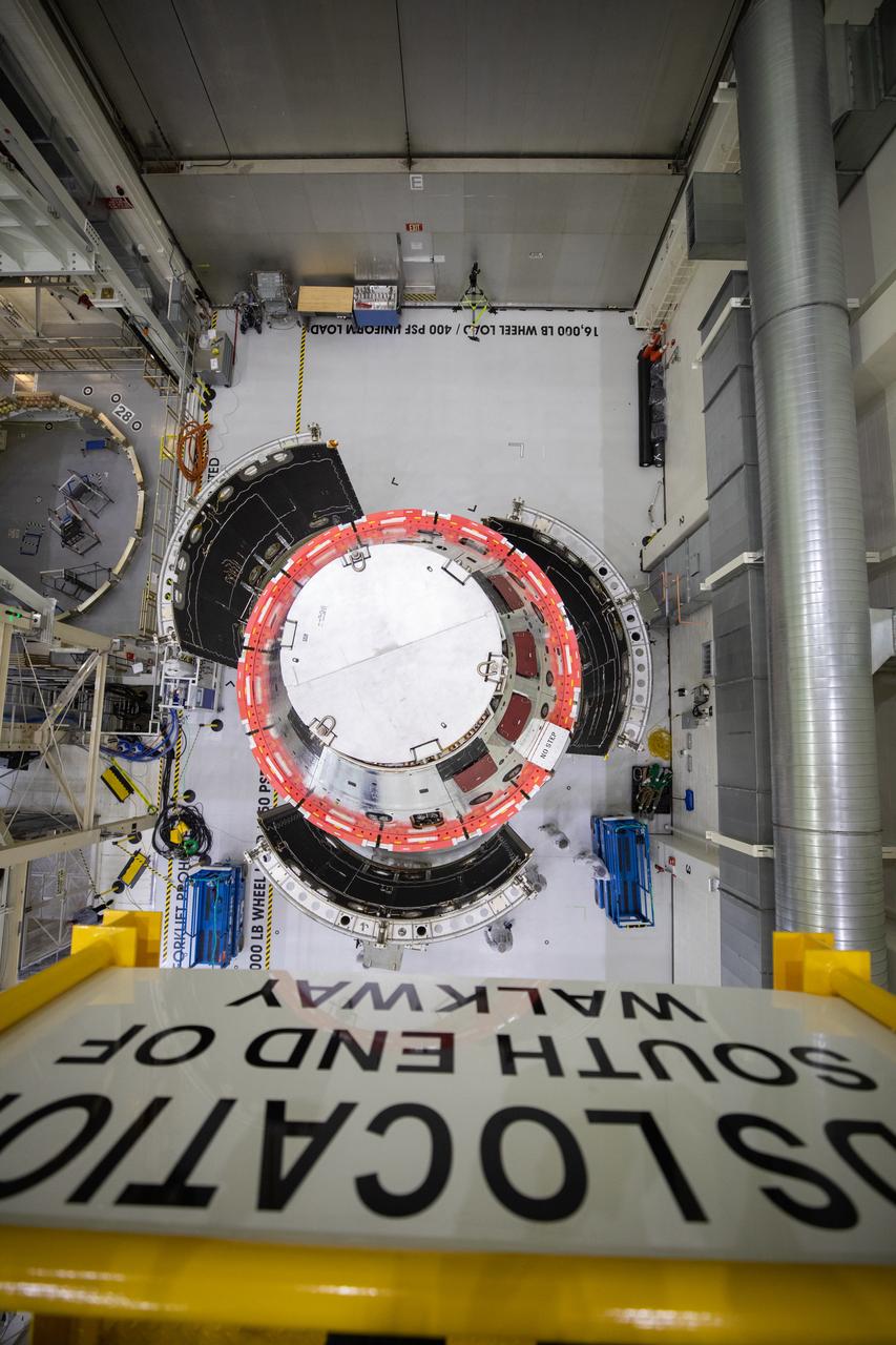 Shown is an overhead view of three spacecraft adapter jettison fairing panels fitted onto Orion’s European Service Module (ESM) on Oct. 13, 2020, inside the Neil Armstrong Operations and Checkout Building (O&C) at NASA’s Kennedy Space Center in Florida. The panels were inspected and moved into place for installation by technicians with Lockheed Martin. Recently, teams from across the globe installed the four solar array wings, which are housed inside the protective covering of the fairings. Once secured, they will encapsulate the ESM to protect it from harsh environments such as heat, wind, and acoustics as the spacecraft is propelled out of Earth’s atmosphere atop the Space Launch System (SLS) rocket during NASA’s Artemis I mission.