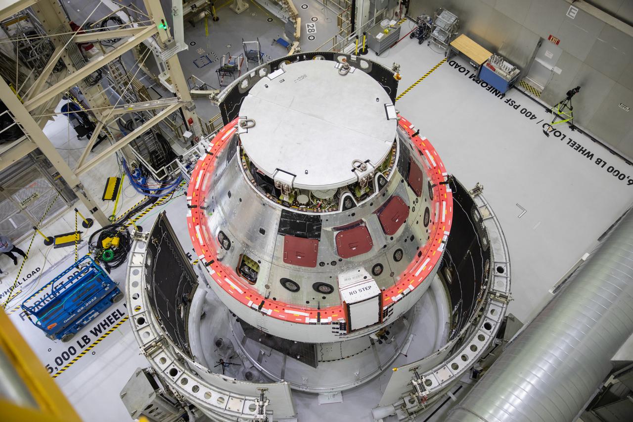 Shown is an overhead view of three spacecraft adapter jettison fairing panels fitted onto Orion’s European Service Module (ESM) on Oct. 13, 2020, inside the Neil Armstrong Operations and Checkout Building (O&C) at NASA’s Kennedy Space Center in Florida. The panels were inspected and moved into place for installation by technicians with Lockheed Martin. Recently, teams from across the globe installed the four solar array wings, which are housed inside the protective covering of the fairings. Once secured, they will encapsulate the ESM to protect it from harsh environments such as heat, wind, and acoustics as the spacecraft is propelled out of Earth’s atmosphere atop the Space Launch System (SLS) rocket during NASA’s Artemis I mission.