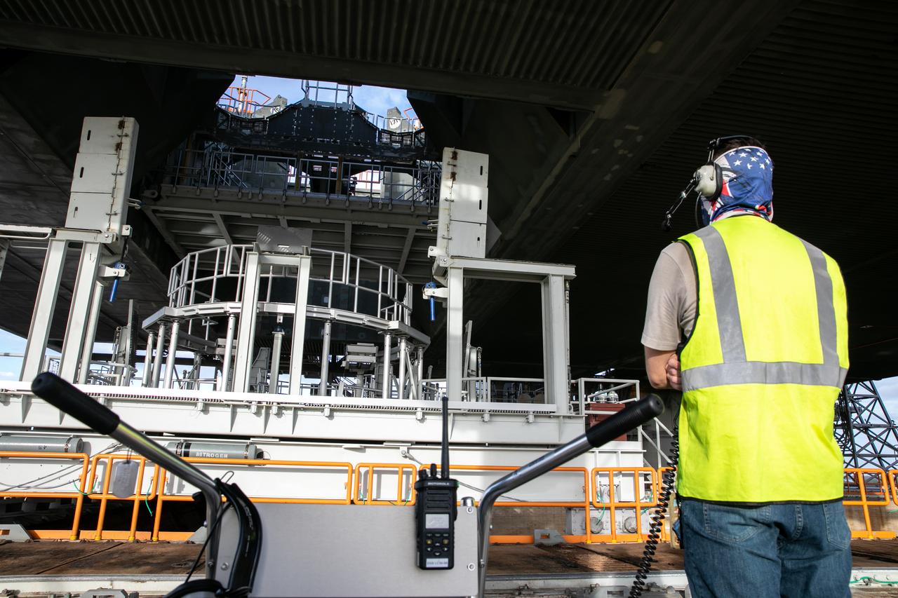 Workers assists with raising the engine service platform beneath the mobile launcher for Artemis I at Launch Pad 39B at NASA’s Kennedy Space Center in Florida on Oct. 23, 2020. The nearly 400-foot-tall mobile launcher is at the pad while engineers with Exploration Ground Systems and Jacobs complete several tasks, including a timing test to validate the launch team’s countdown timeline, and a thorough, top-to-bottom wash down of the mobile launcher to remove any debris remaining from construction and installation of the umbilical arms. Artemis I will test the Orion spacecraft and Space Launch System as an integrated system ahead of crewed flights to the Moon. Under the Artemis program, NASA will land the first woman and the next man on the Moon in 2024.