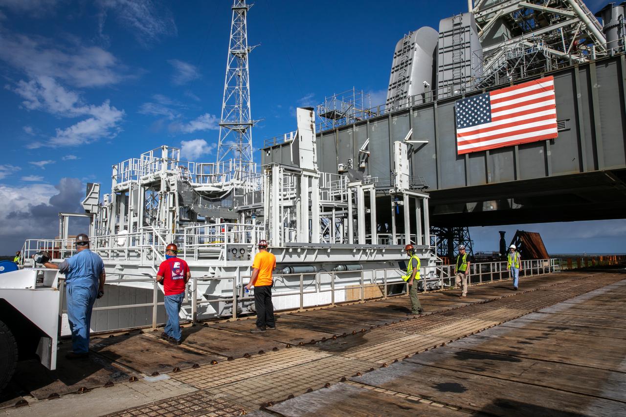 The engine service platform has been lowered and removed from the mobile launcher for Artemis I at Launch Pad 39B at NASA’s Kennedy Space Center in Florida on Oct. 23, 2020. The platform is in view on a flatbed truck. The nearly 400-foot-tall mobile launcher is at the pad while engineers with Exploration Ground Systems and Jacobs complete several tasks, including a timing test to validate the launch team’s countdown timeline, and a thorough, top-to-bottom wash down of the mobile launcher to remove any debris remaining from construction and installation of the umbilical arms. Artemis I will test the Orion spacecraft and Space Launch System as an integrated system ahead of crewed flights to the Moon. Under the Artemis program, NASA will land the first woman and the next man on the Moon in 2024.