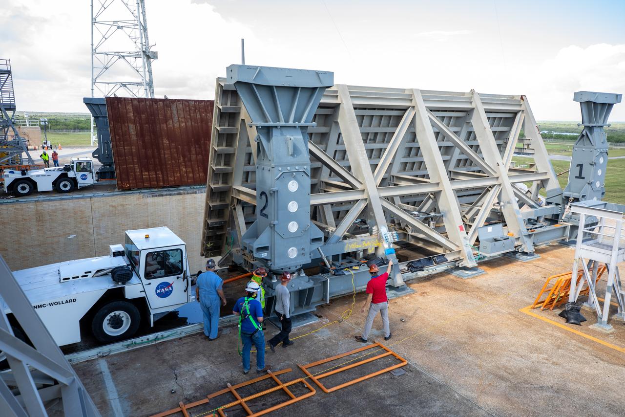 Technicians help move the side flame deflectors into place during a countdown demonstration test using the mobile launcher for the Artemis I mission at Launch Pad 39B at NASA’s Kennedy Space Center in Florida on Oct. 23, 2020. The nearly 400-foot-tall mobile launcher is at the pad while engineers with Exploration Ground Systems and Jacobs complete several tasks, including a timing test to validate the launch team’s countdown timeline, and a thorough, top-to-bottom wash down of the mobile launcher to remove any debris remaining from construction and installation of the umbilical arms. Artemis I will test the Orion spacecraft and Space Launch System as an integrated system ahead of crewed flights to the Moon. Under the Artemis program, NASA will land the first woman and the next man on the Moon in 2024.