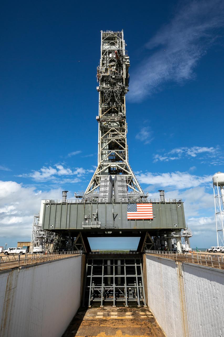 A view of the mobile launcher for Artemis I with the two side flame deflectors positioned underneath during a countdown demonstration test at Launch Pad 39B at NASA’s Kennedy Space Center in Florida on Oct. 23, 2020. Also in view is the main flame deflector in the flame trench. The nearly 400-foot-tall mobile launcher is at the pad while engineers with Exploration Ground Systems and Jacobs complete several tasks, including a timing test to validate the launch team’s countdown timeline, and a thorough, top-to-bottom wash down of the mobile launcher to remove any debris remaining from construction and installation of the umbilical arms. Artemis I will test the Orion spacecraft and Space Launch System as an integrated system ahead of crewed flights to the Moon. Under the Artemis program, NASA will land the first woman and the next man on the Moon in 2024.