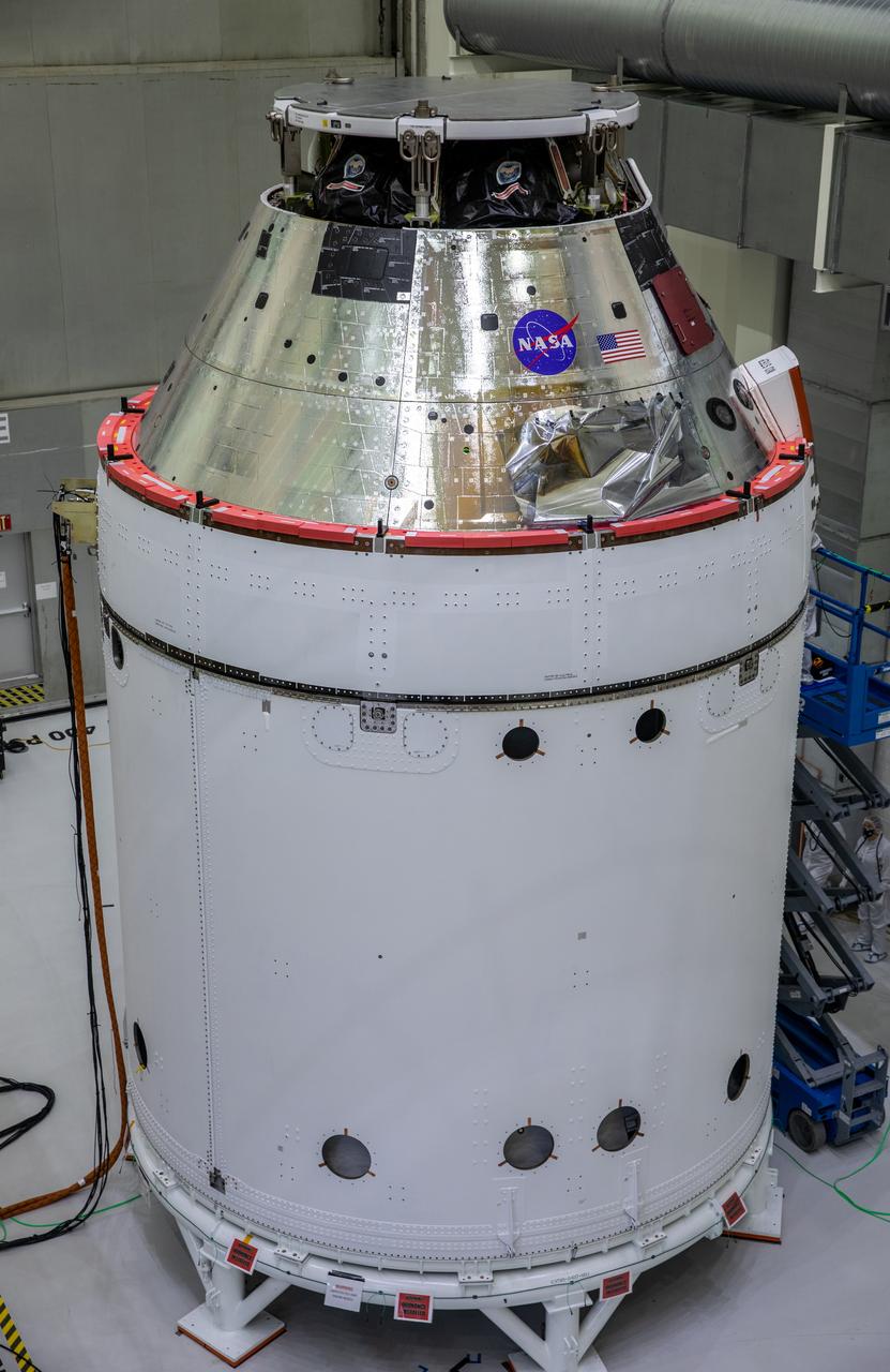 The NASA insignia, also called the “meatball,” and the American Flag are applied to the Orion crew module back shell for the Artemis I mission on Oct. 28, 2020, inside the Neil Armstrong Operations and Checkout Building at NASA’s Kennedy Space Center in Florida. Attached below Orion are the crew module adapter and the European Service Module (ESM) with spacecraft adapter jettison fairings installed. Recently, teams from across the globe installed the four solar array wings, which are housed inside the protective covering of the fairings. The fairing panels will encapsulate the ESM to protect it from harsh environments such as heat, wind, and acoustics as the spacecraft is propelled out of Earth’s atmosphere atop the Space Launch System rocket during NASA’s Artemis I mission.