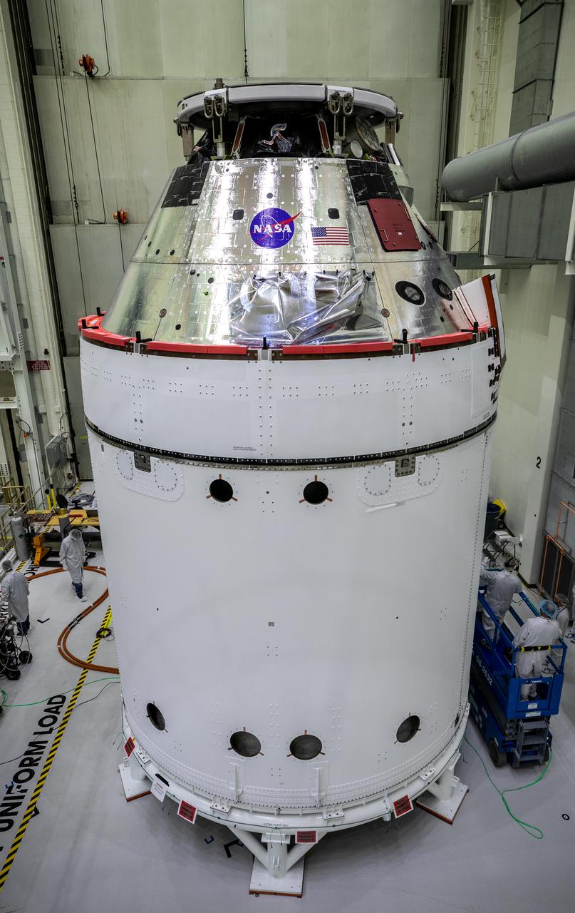 The NASA insignia, also called the “meatball,” and the American Flag are applied to the Orion crew module back shell for the Artemis I mission on Oct. 28, 2020, inside the Neil Armstrong Operations and Checkout Building at NASA’s Kennedy Space Center in Florida. Attached below Orion are the crew module adapter and the European Service Module (ESM) with spacecraft adapter jettison fairings installed. Recently, teams from across the globe installed the four solar array wings, which are housed inside the protective covering of the fairings. The fairing panels will encapsulate the ESM to protect it from harsh environments such as heat, wind, and acoustics as the spacecraft is propelled out of Earth’s atmosphere atop the Space Launch System rocket during NASA’s Artemis I mission.